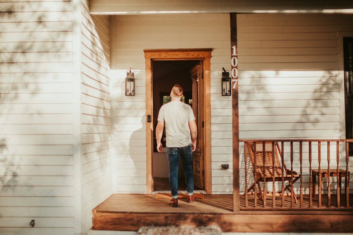 Man standing on the porch of a residential home in natural light