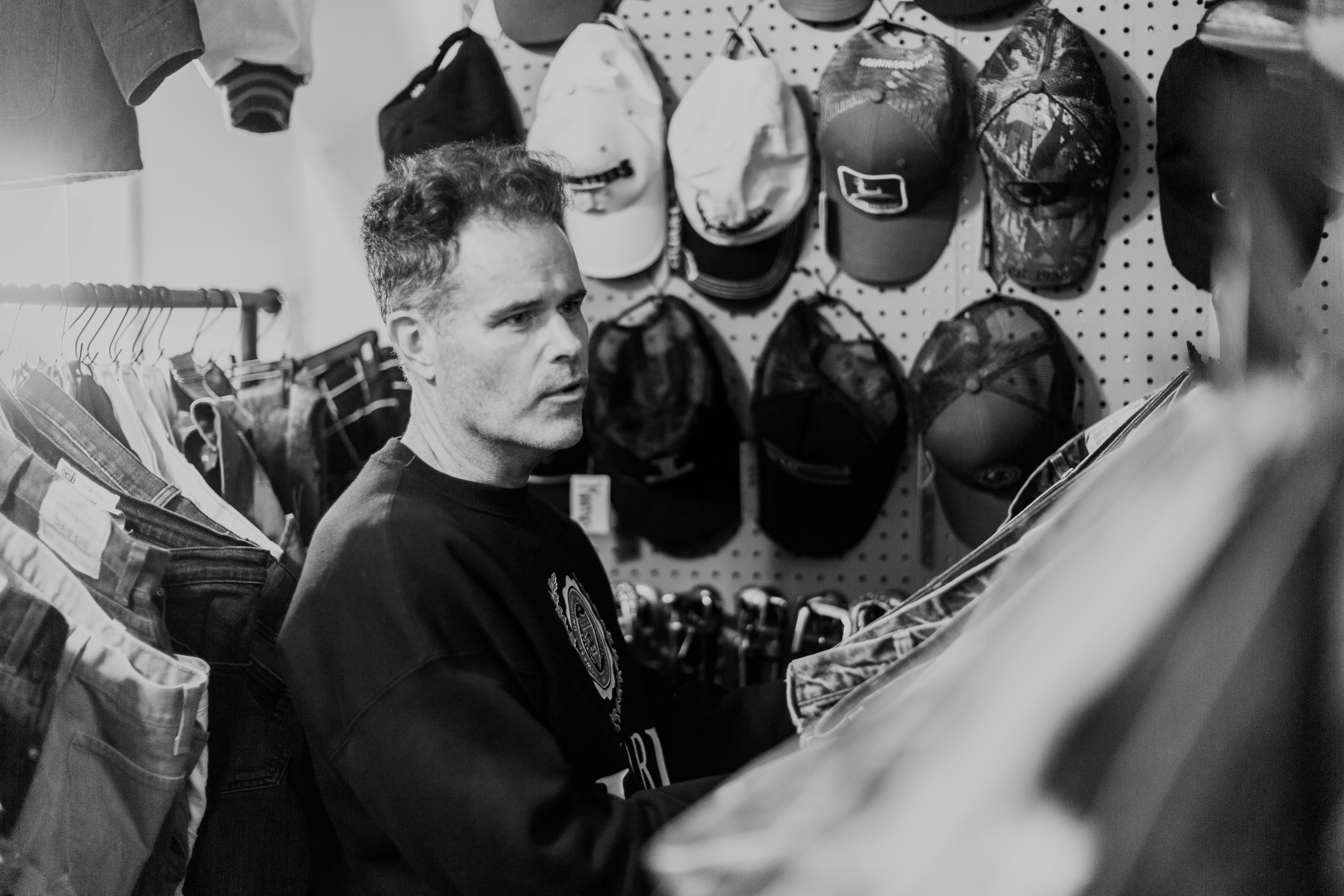 A man standing in front of a wall of hats