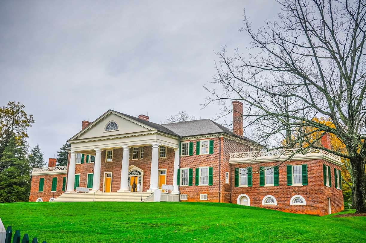 A large red brick house sitting on top of a lush green field