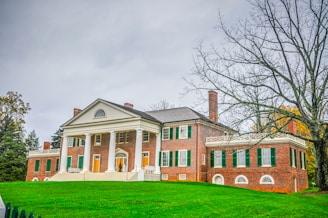 A large red brick house sitting on top of a lush green field