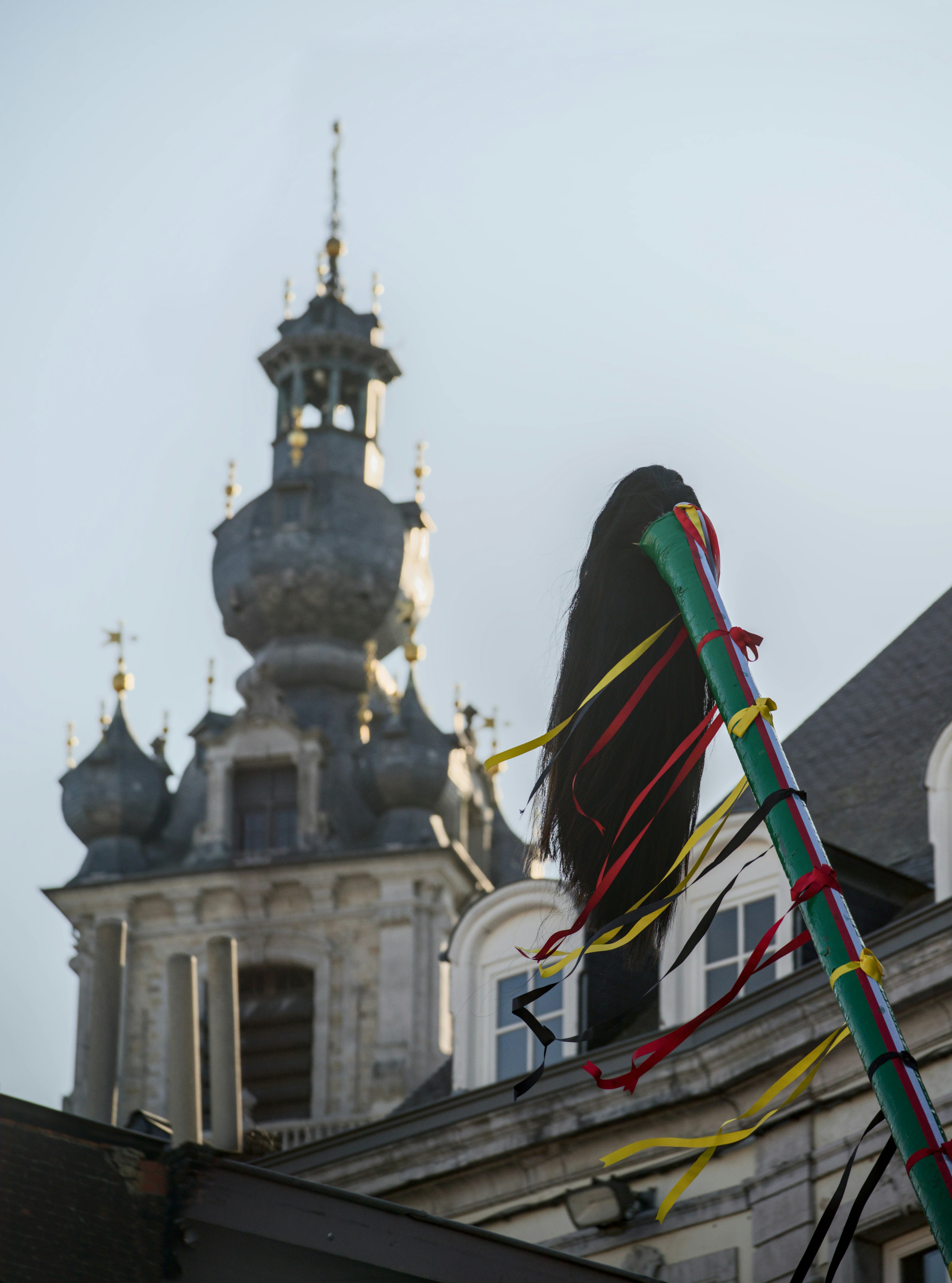 Uma pipa voando em frente a um prédio com uma torre de relógio ao fundo