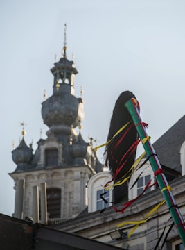 A kite flying in front of a building with a clock tower in the background