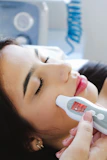 A woman laying in bed with a thermometer in her mouth