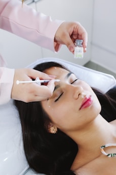 A woman laying on a bed getting her eyebrows done