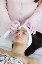 A woman getting a facial peel from a woman in a salon