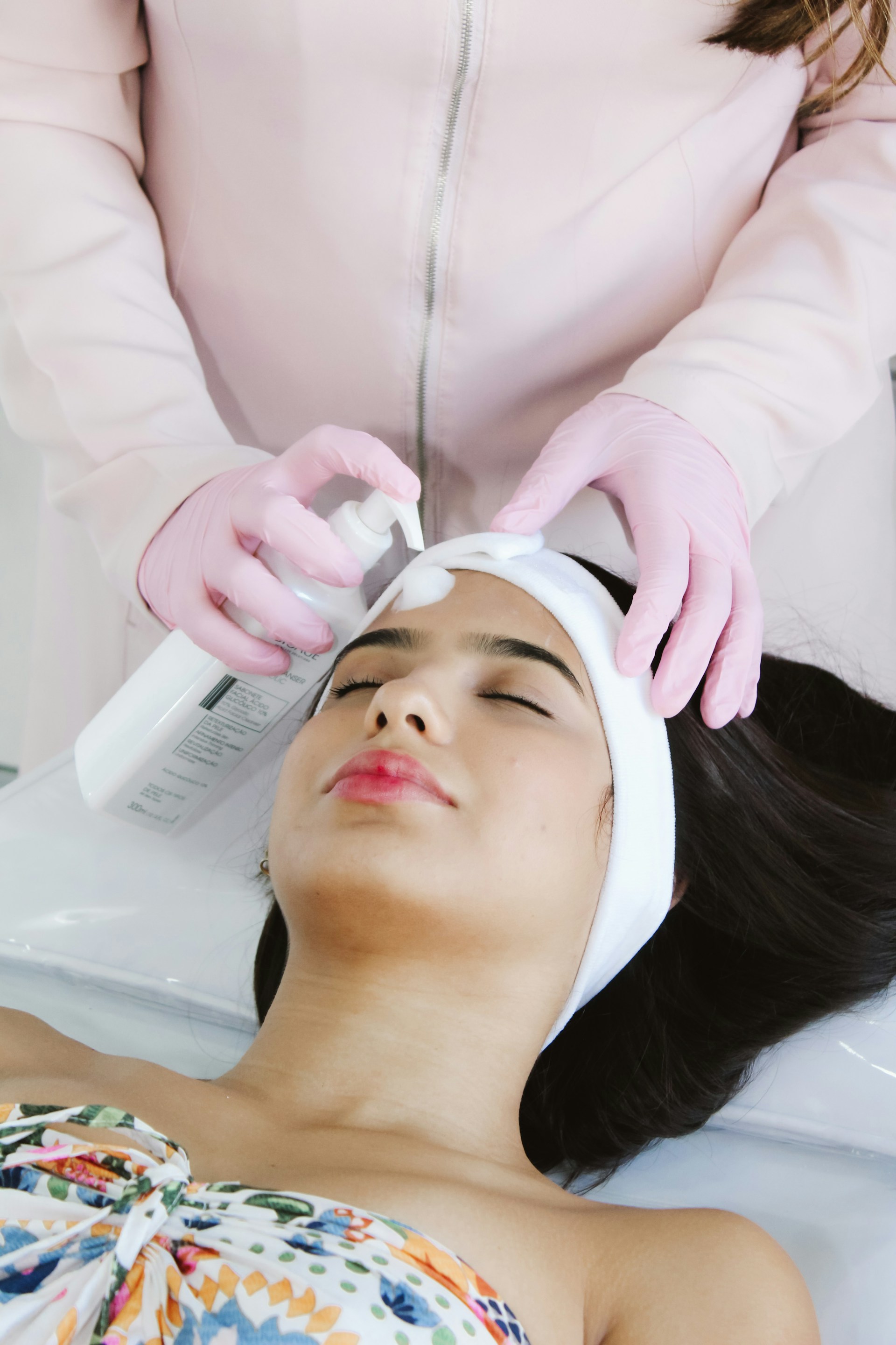 A woman getting a facial peel from a woman in a salon