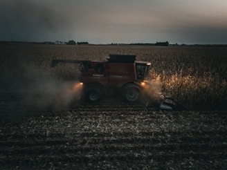 A red tractor is driving through a field