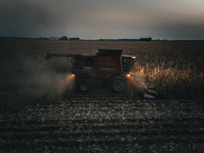 A red tractor is driving through a field