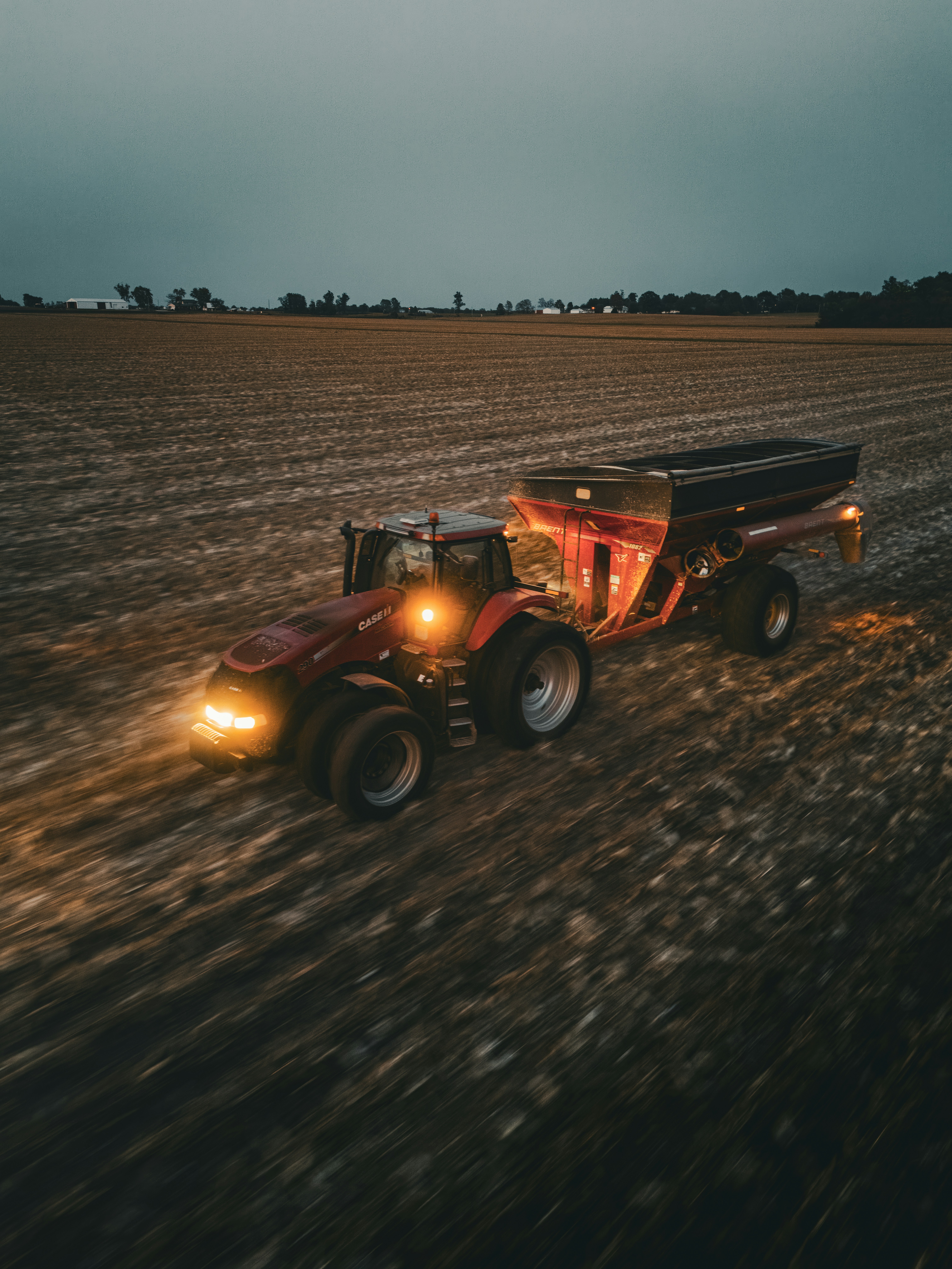 A tractor is driving through a field at night