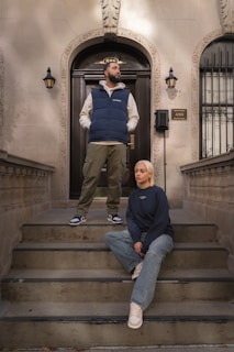 A man and a woman sitting on the steps of a building