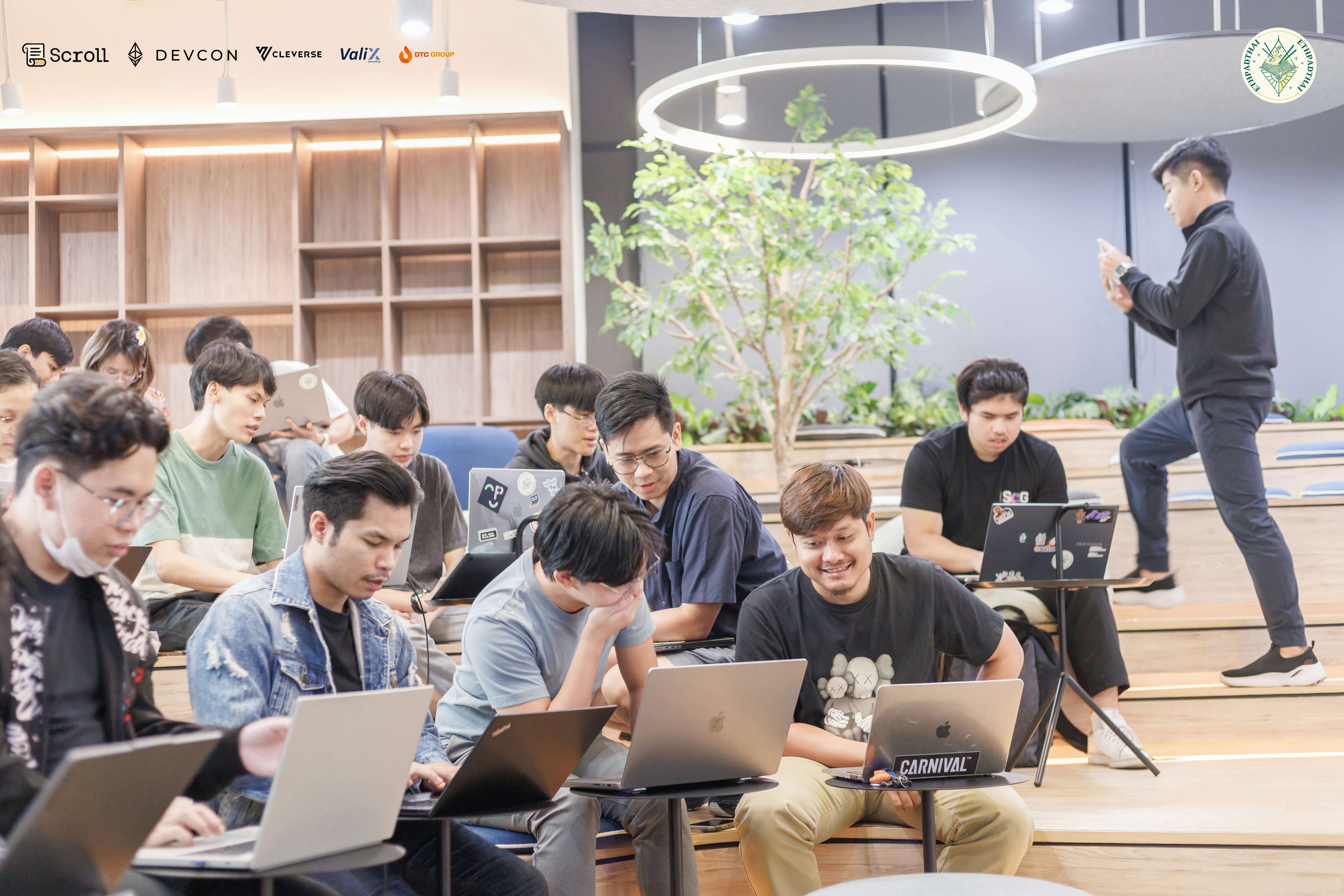 A group of people sitting in front of laptops, 