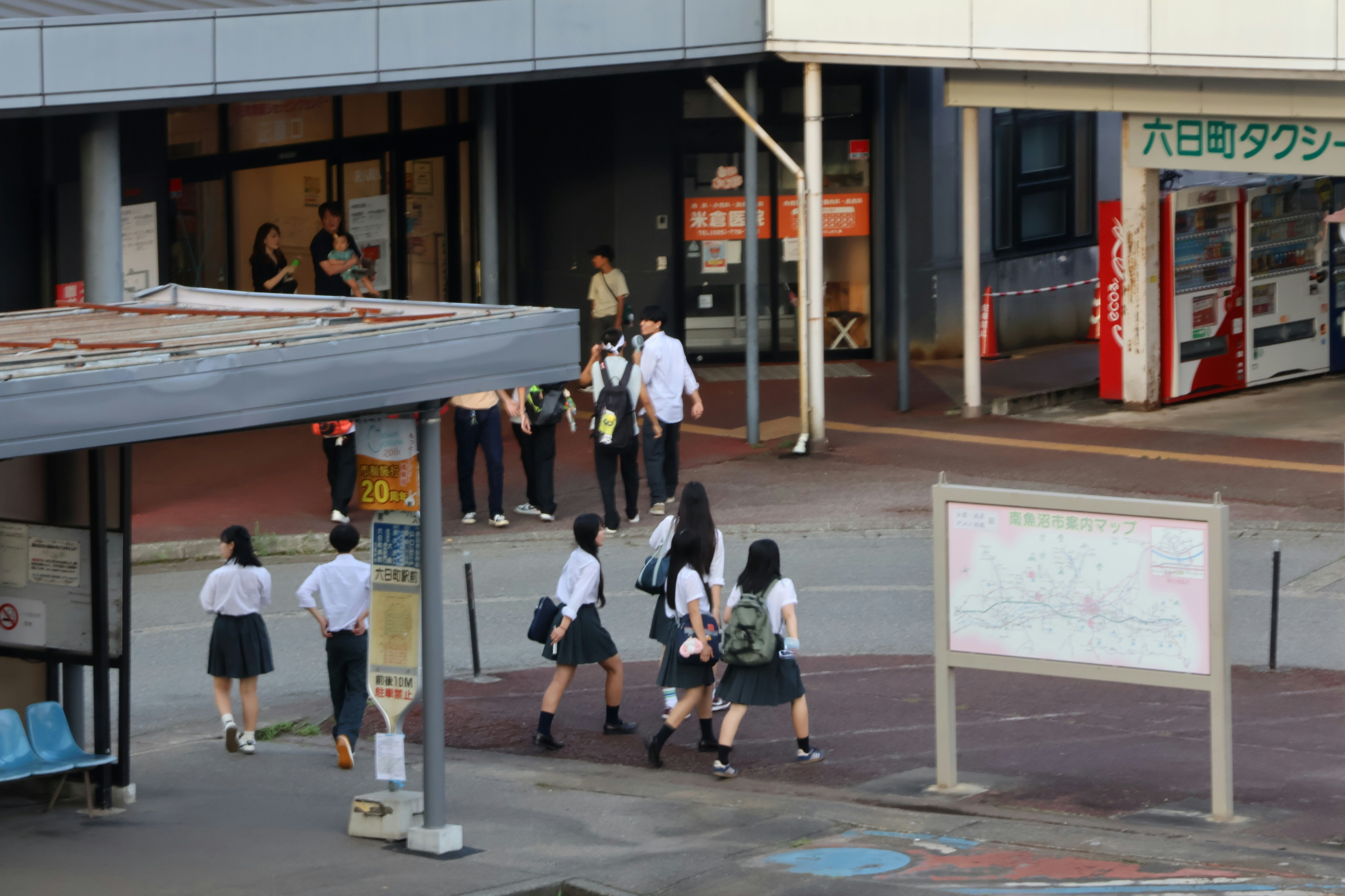 A group of people walking down a street next to a building
