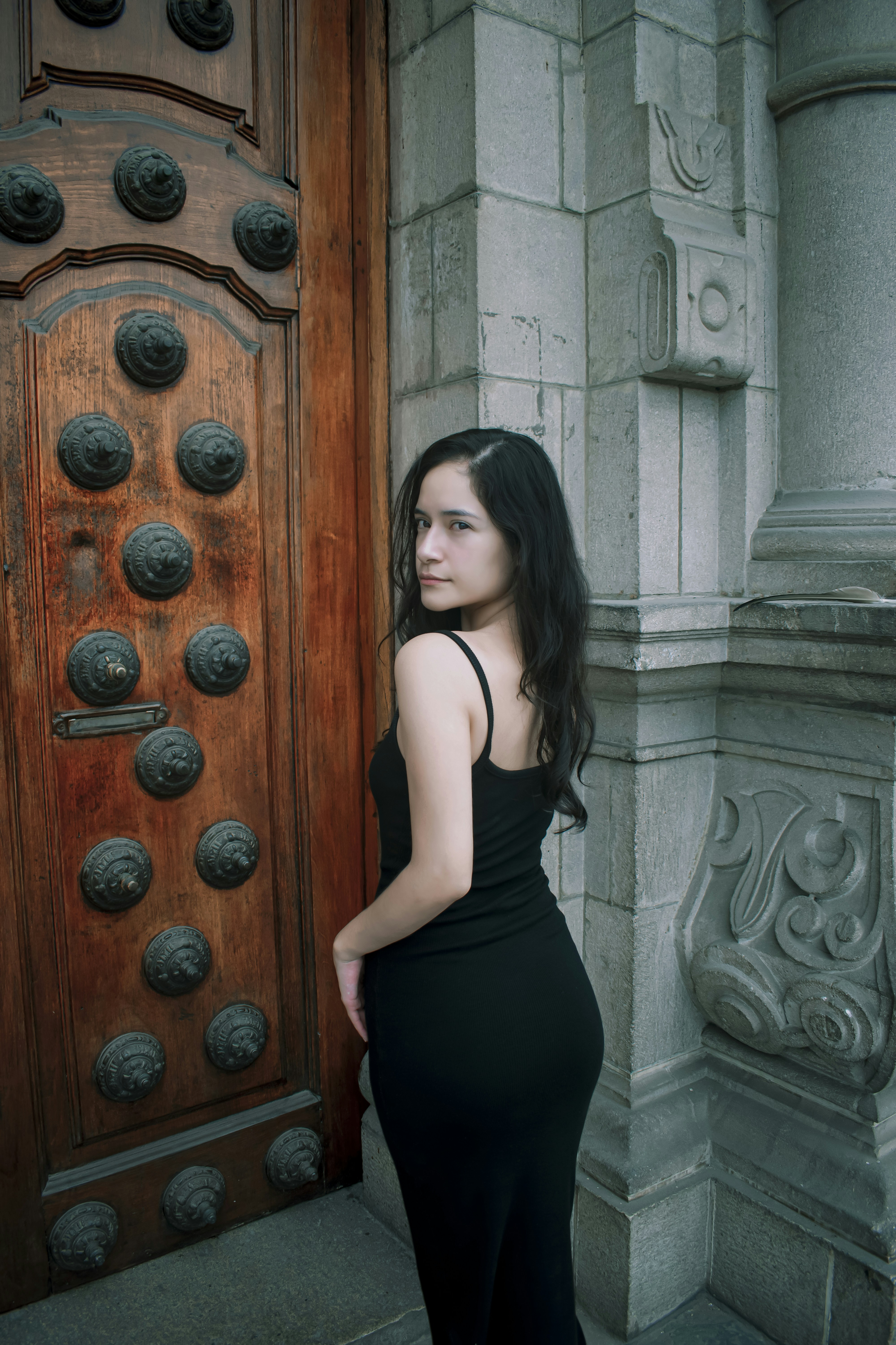 A woman in a black dress standing in front of a door photo – Free Woman ...