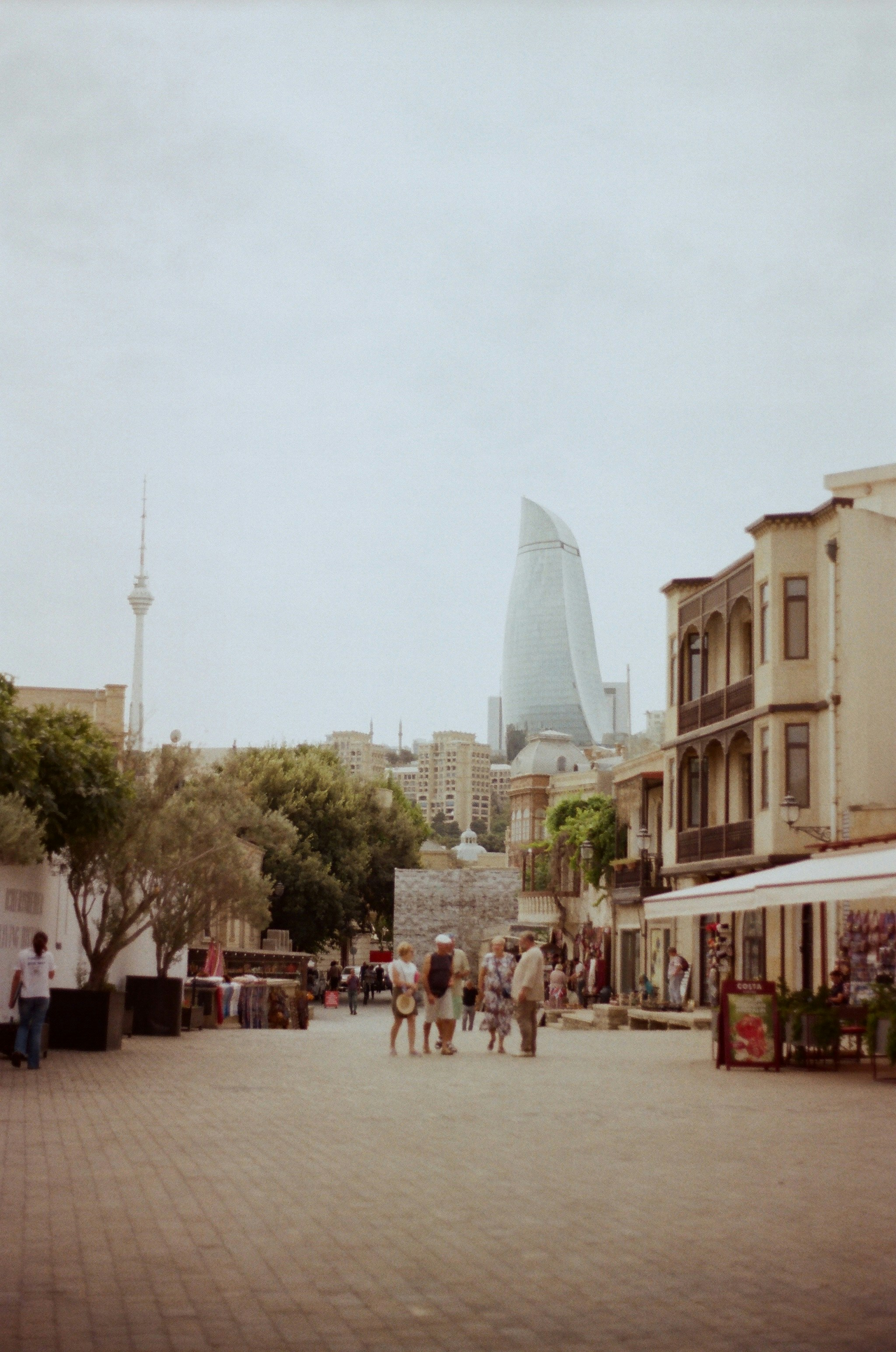 A group of people walking down a street next to tall buildings photo ...