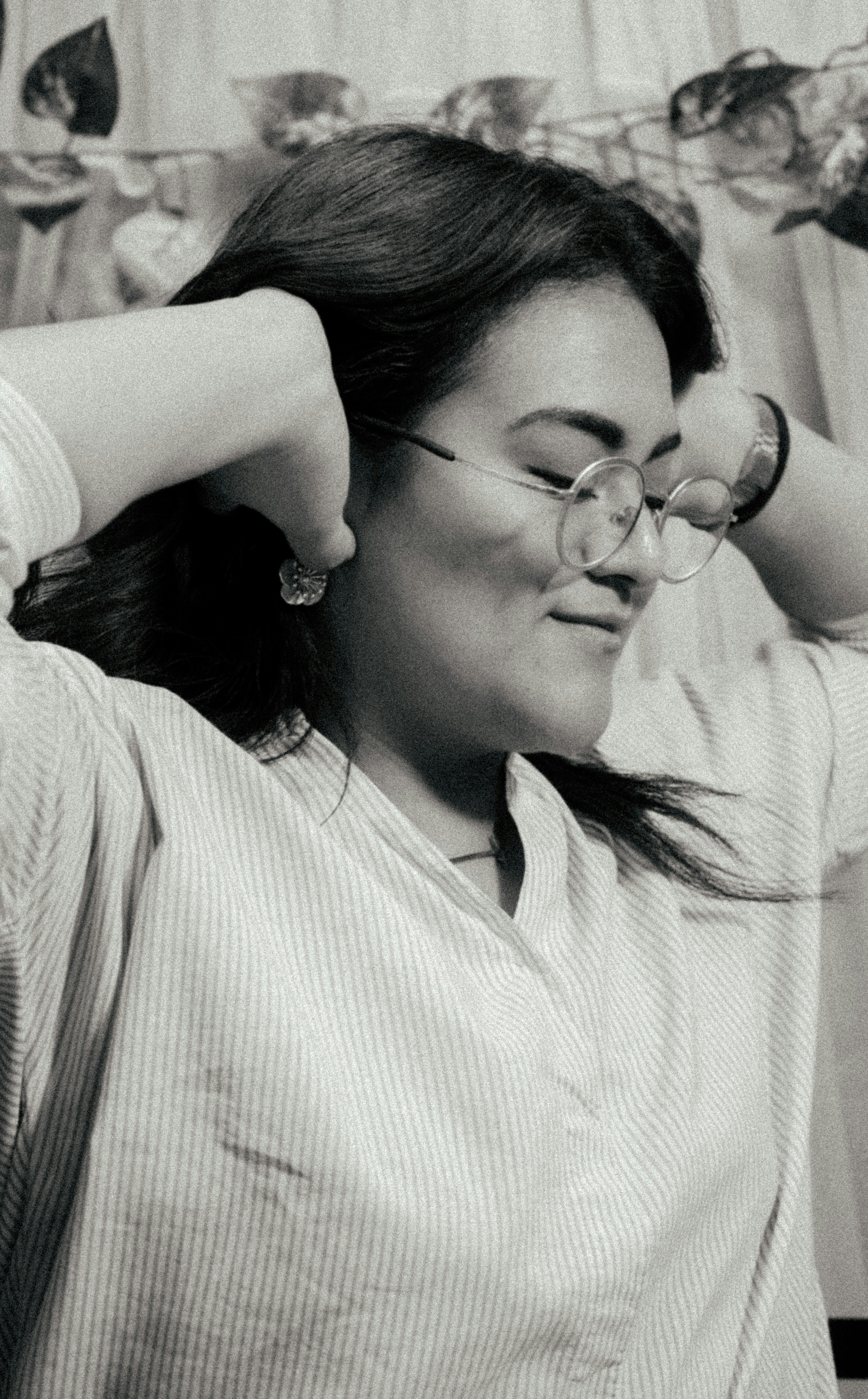 A woman with glasses is holding her hair