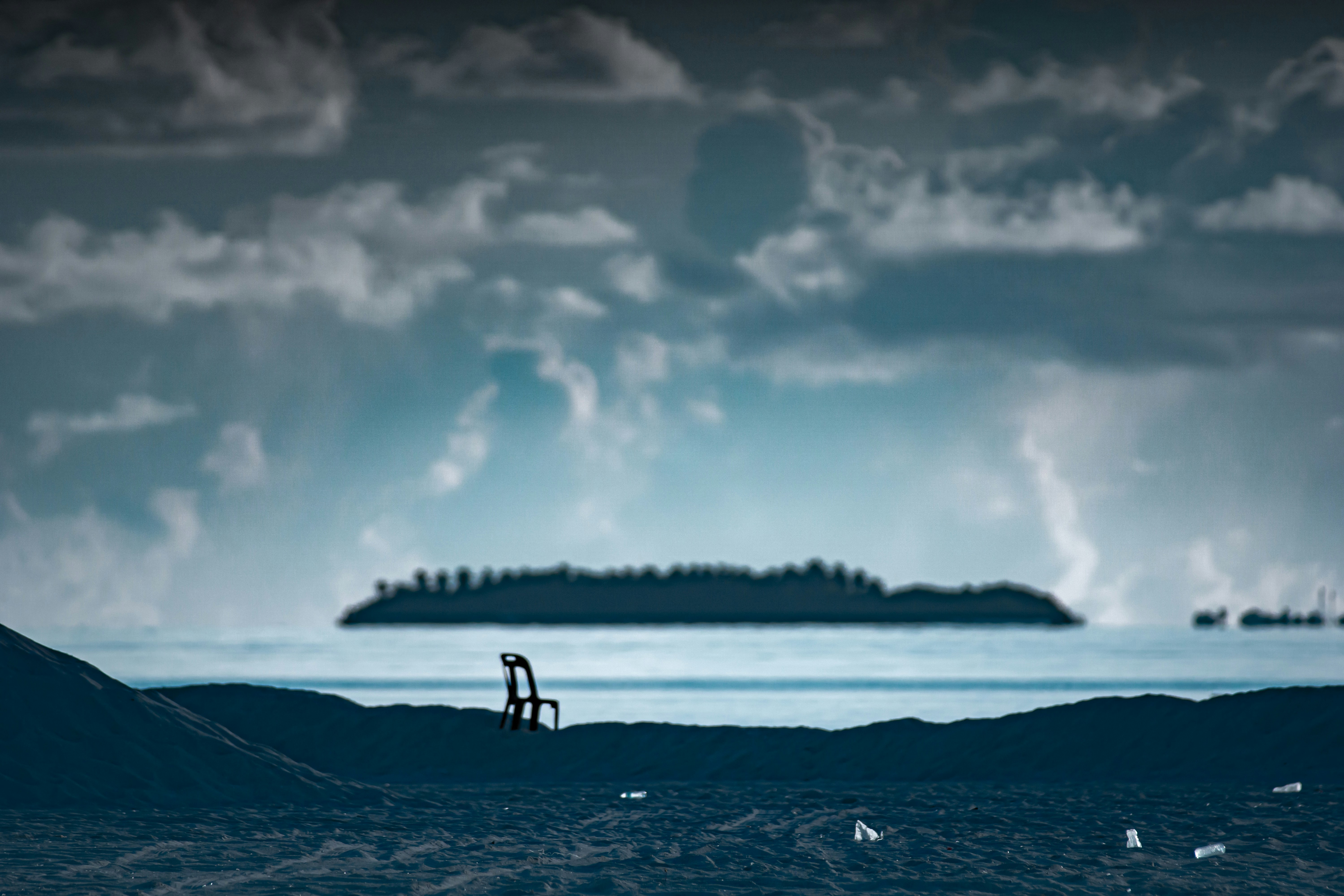 A person standing on a beach with a boat in the background