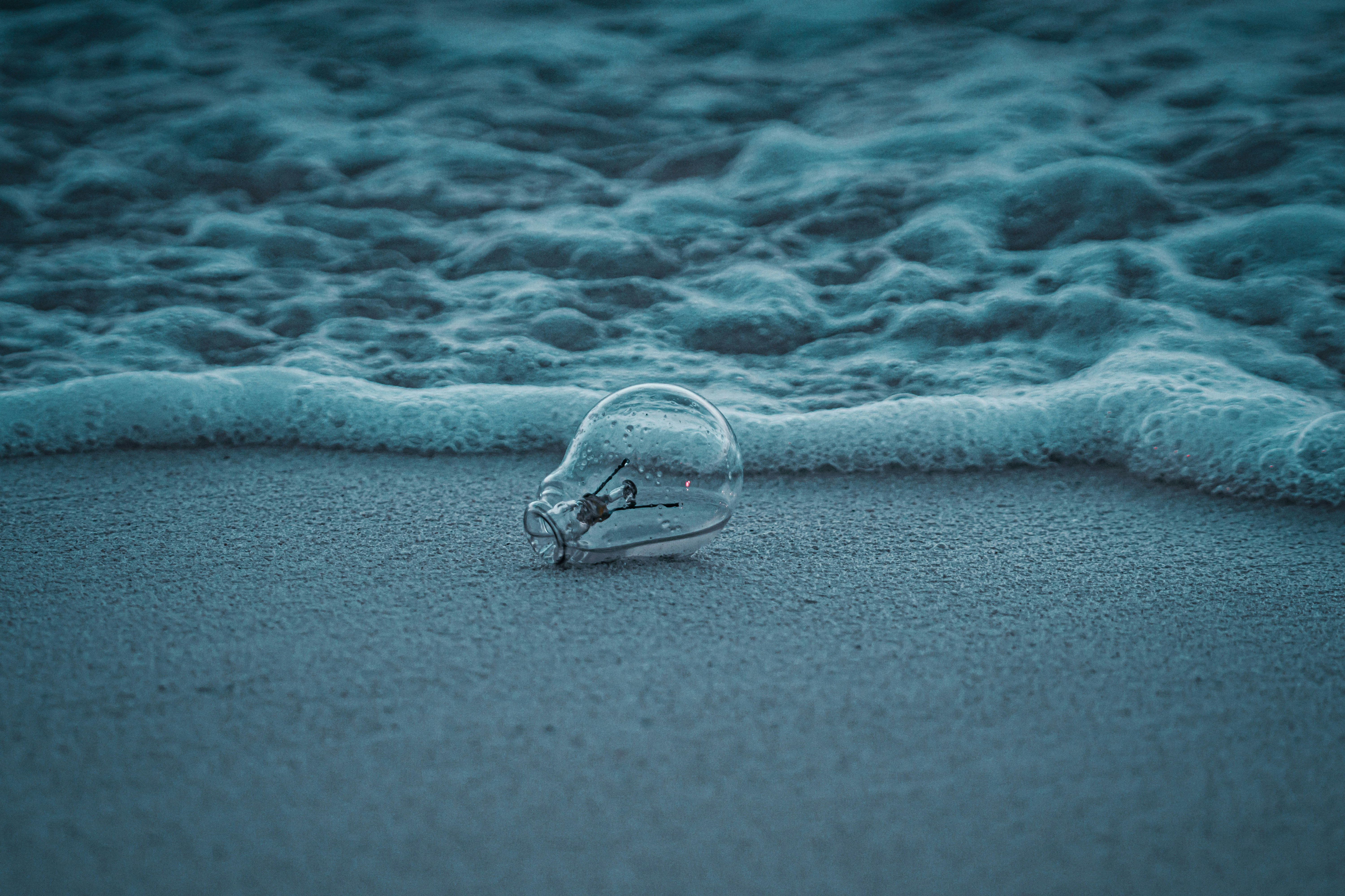 A glass bottle sitting on top of a sandy beach
