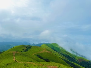 A lush green hillside covered in lots of clouds