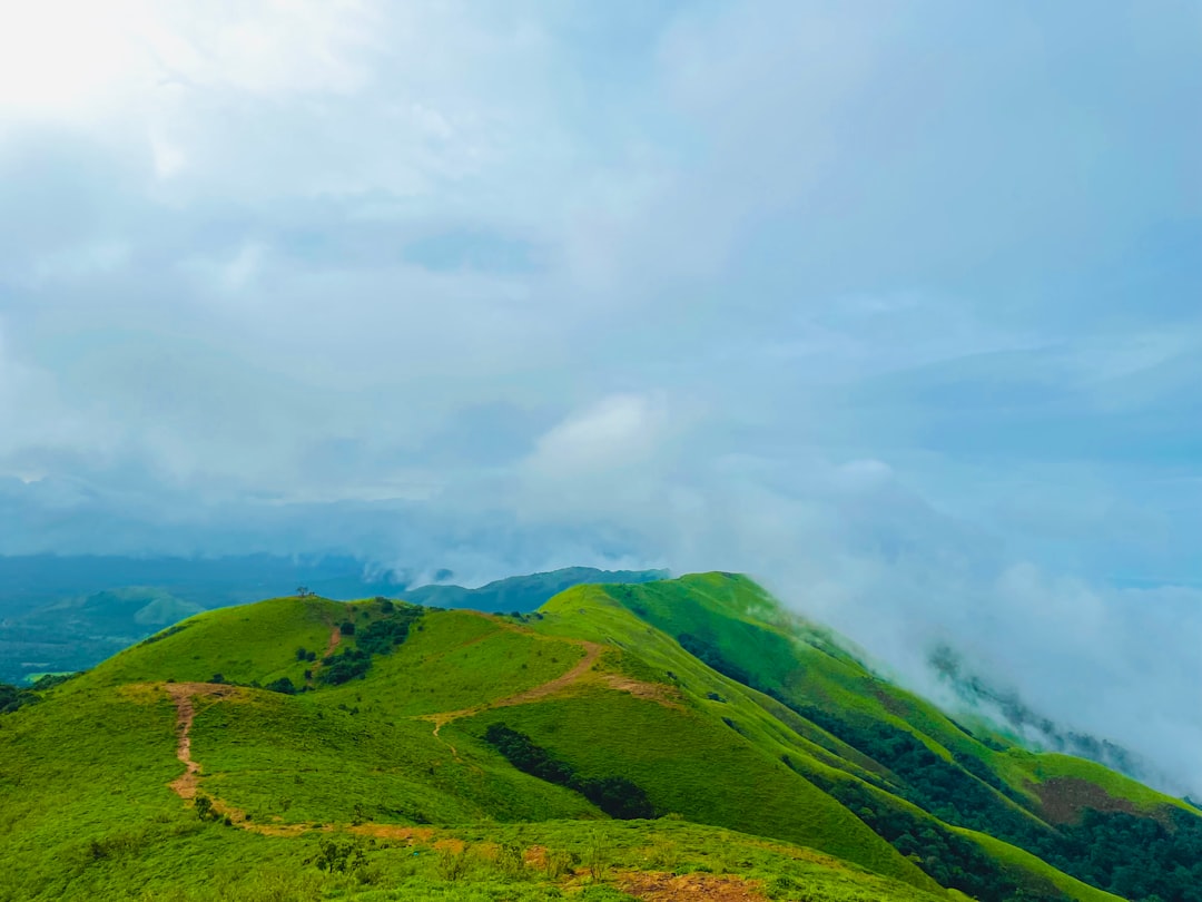 A lush green hillside covered in lots of clouds,