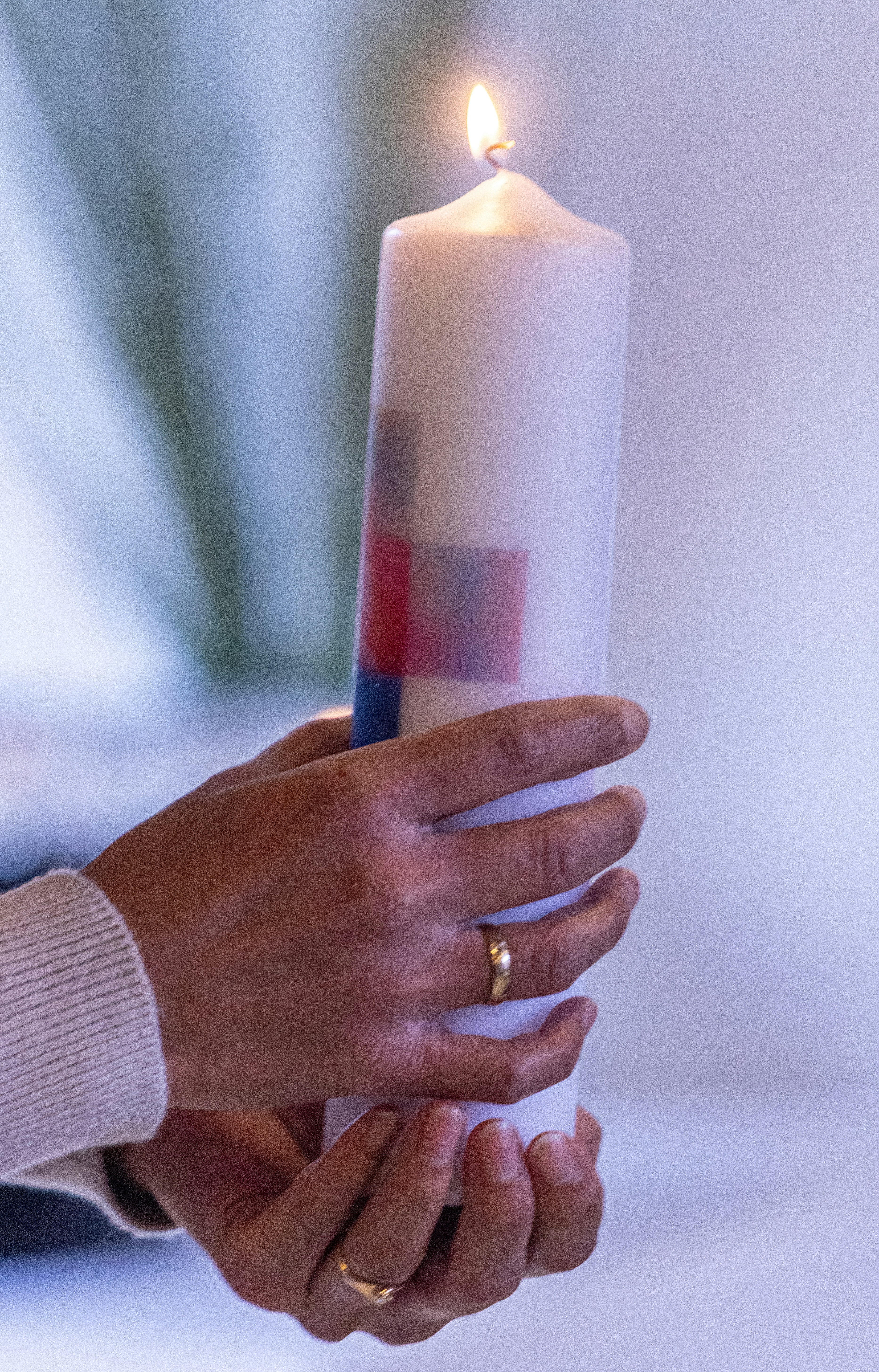 A person holding a lit candle in their hands