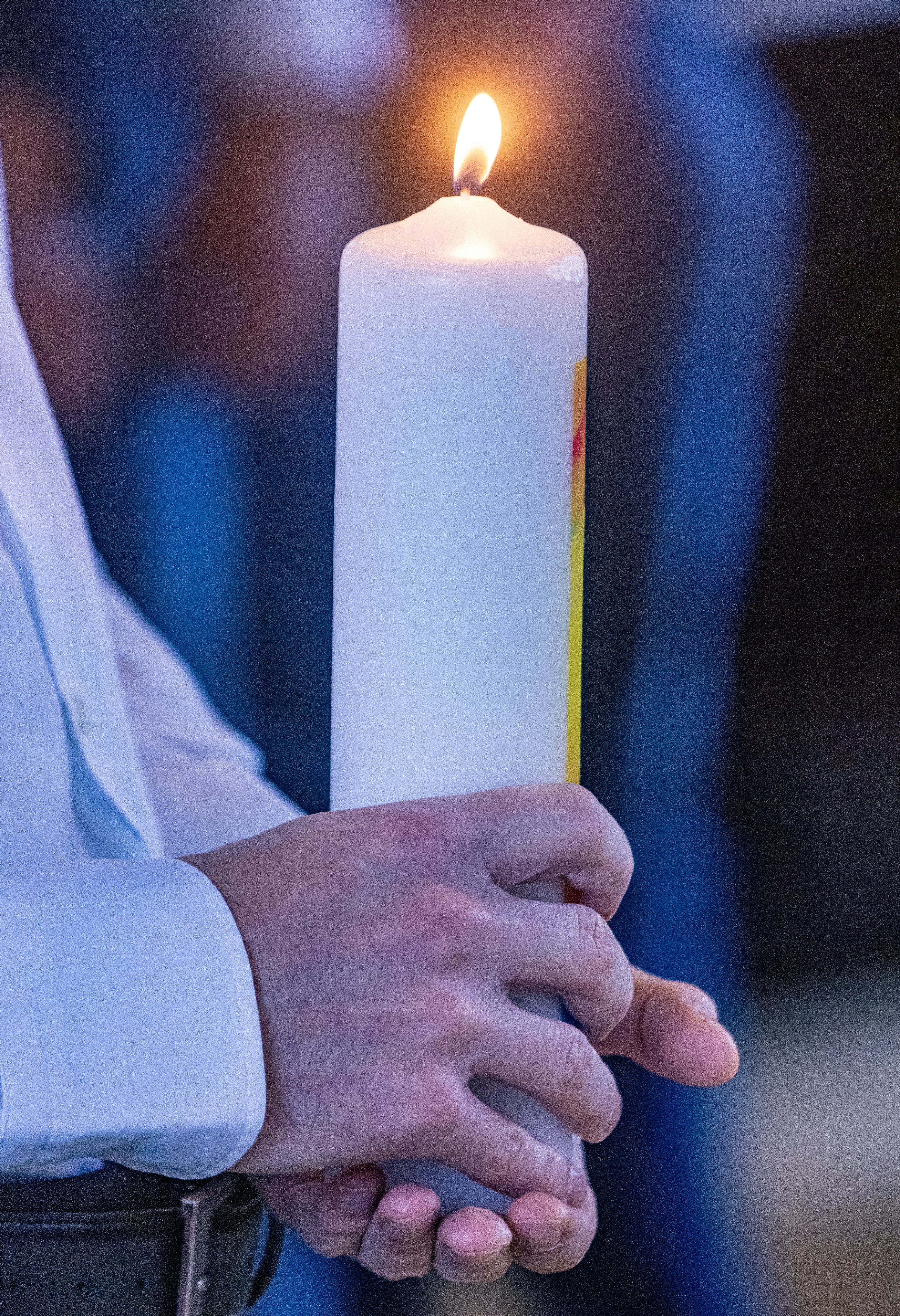 A person holding a lit candle in their hands