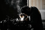 A man welding a piece of metal in a dark room