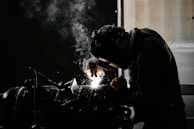A man welding a piece of metal in a dark room
