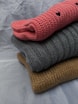 A stack of three knitted sweaters sitting on top of each other