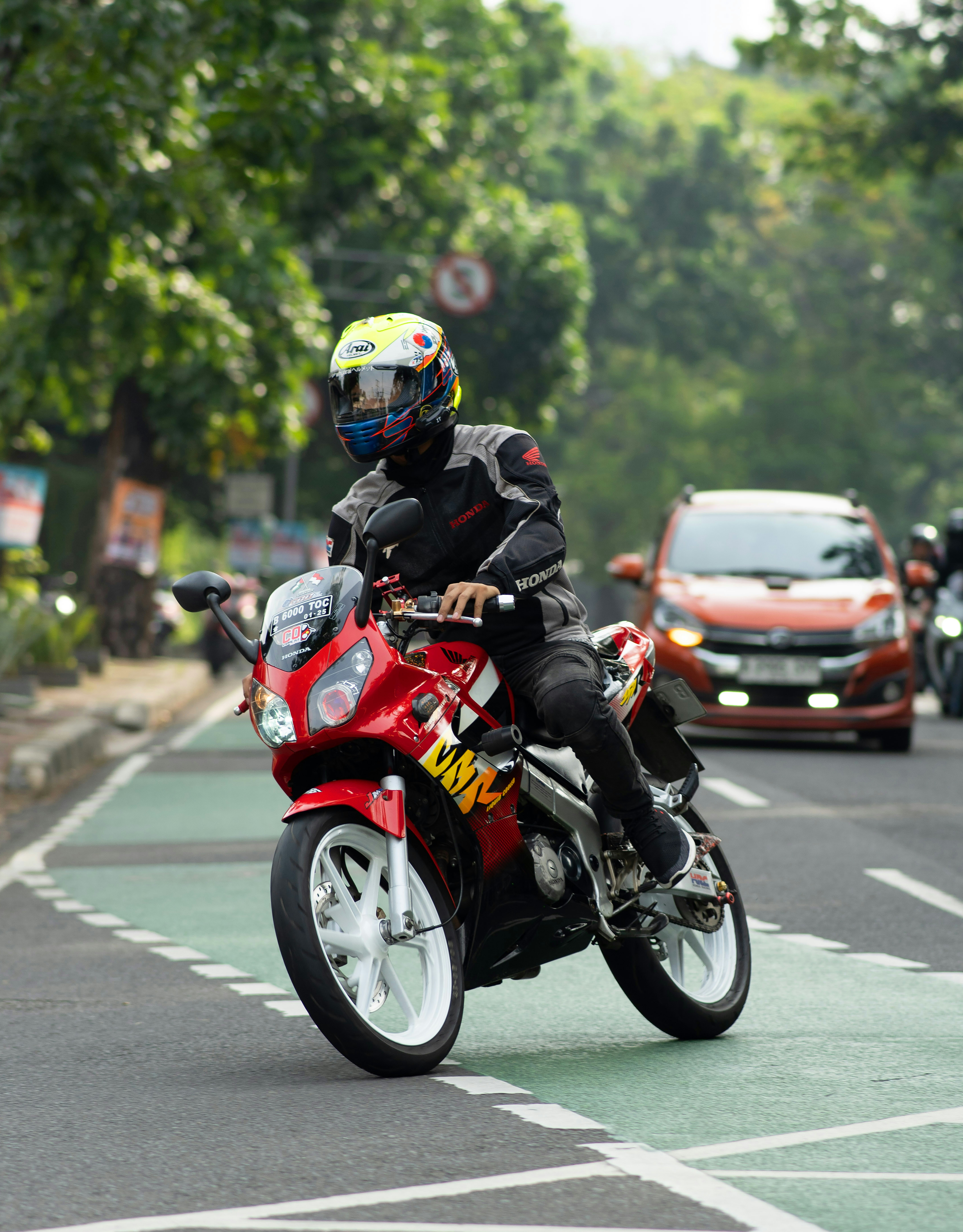 A man riding a red motorcycle down a street