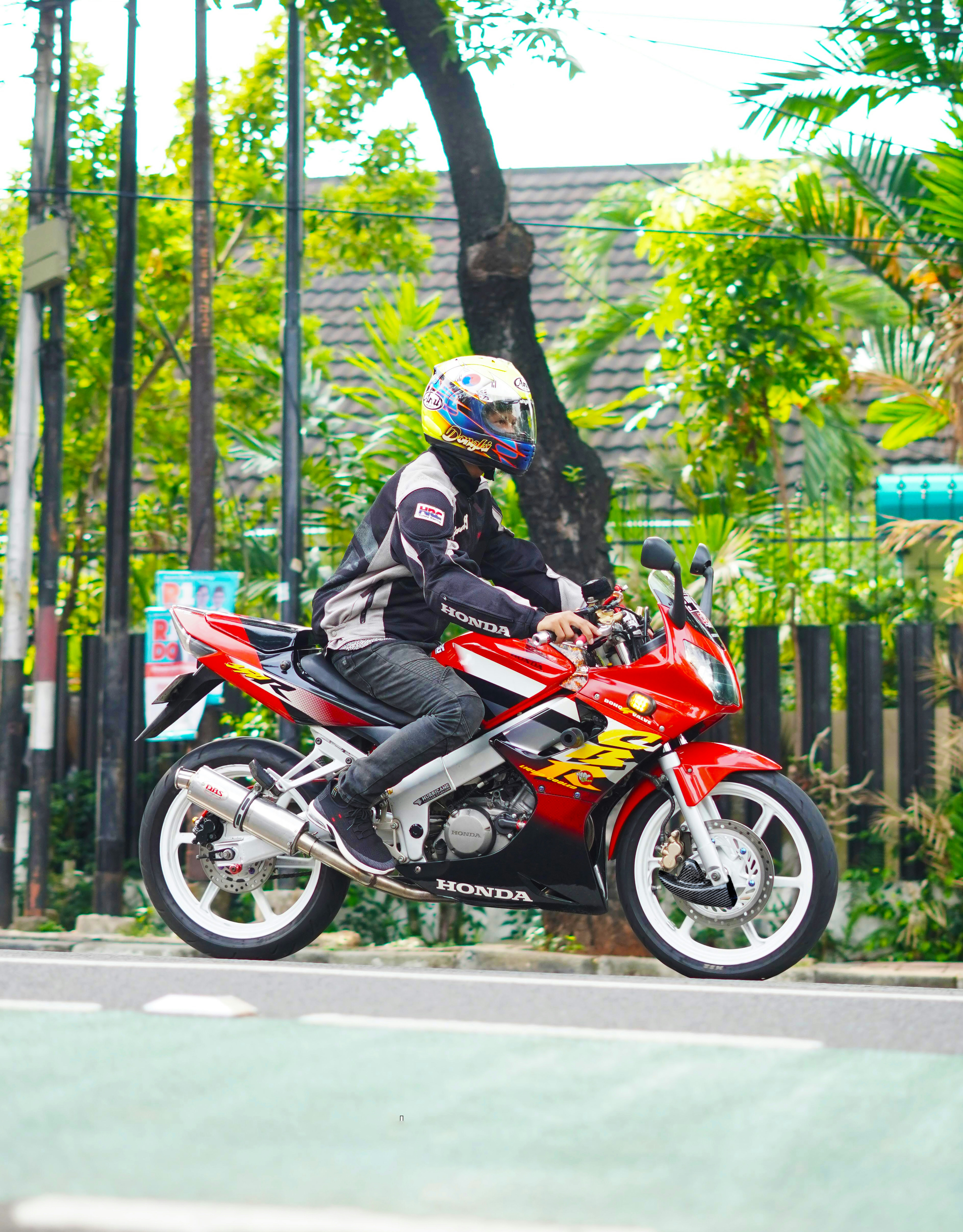 A man riding a red motorcycle down a street