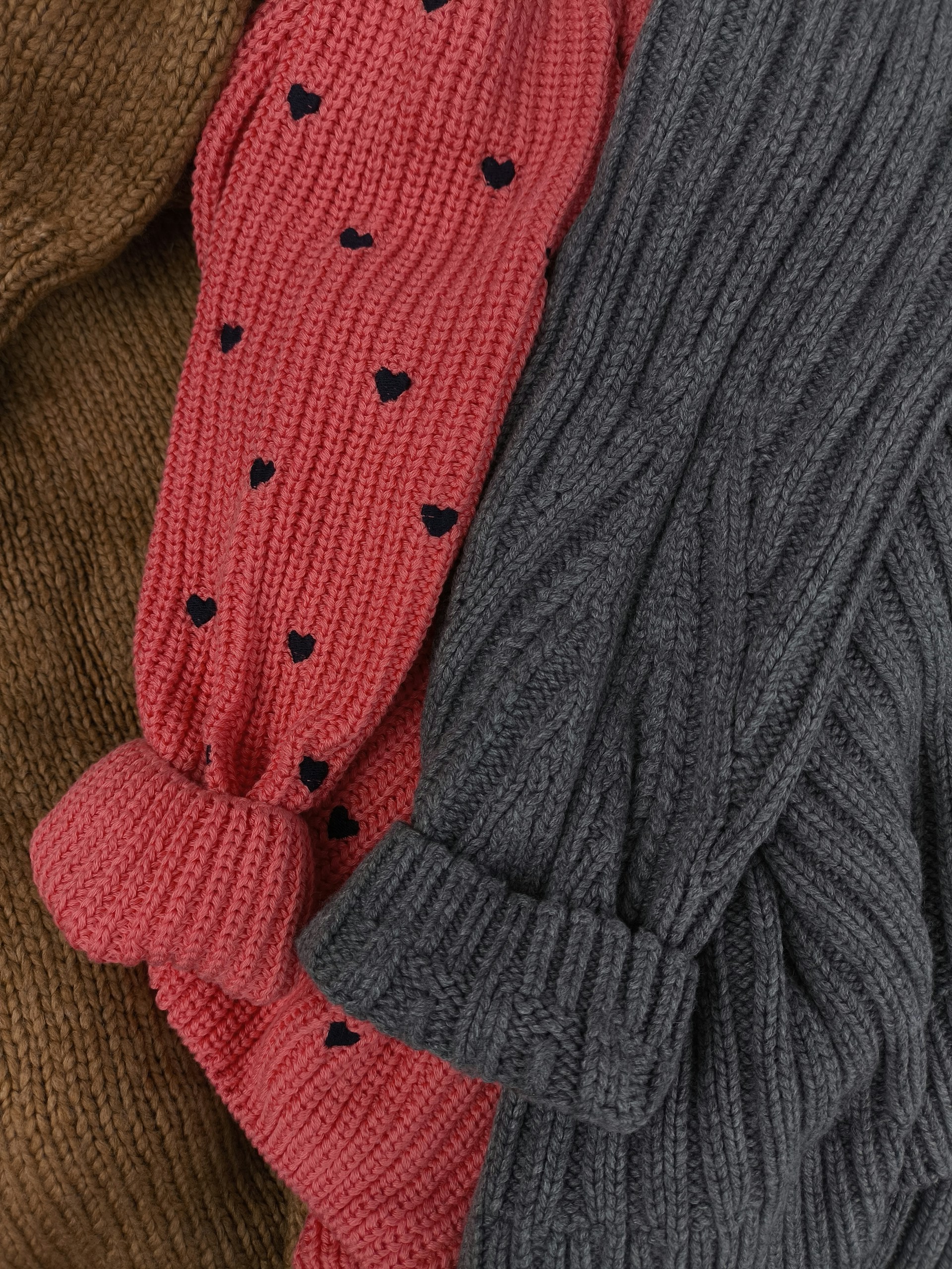 A close up of three sweaters with hearts on them