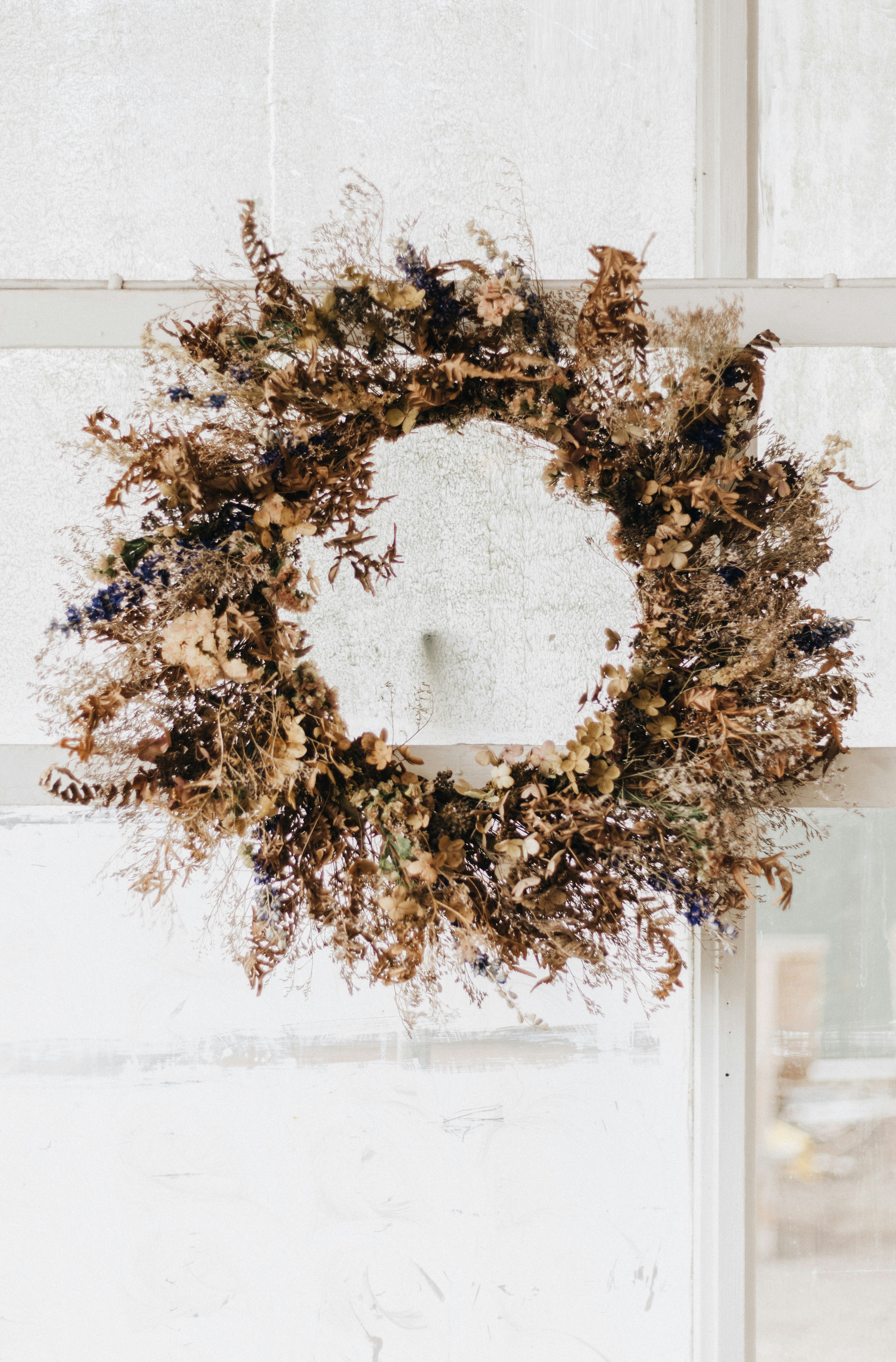 Une couronne séchée accrochée au rebord d’une fenêtre