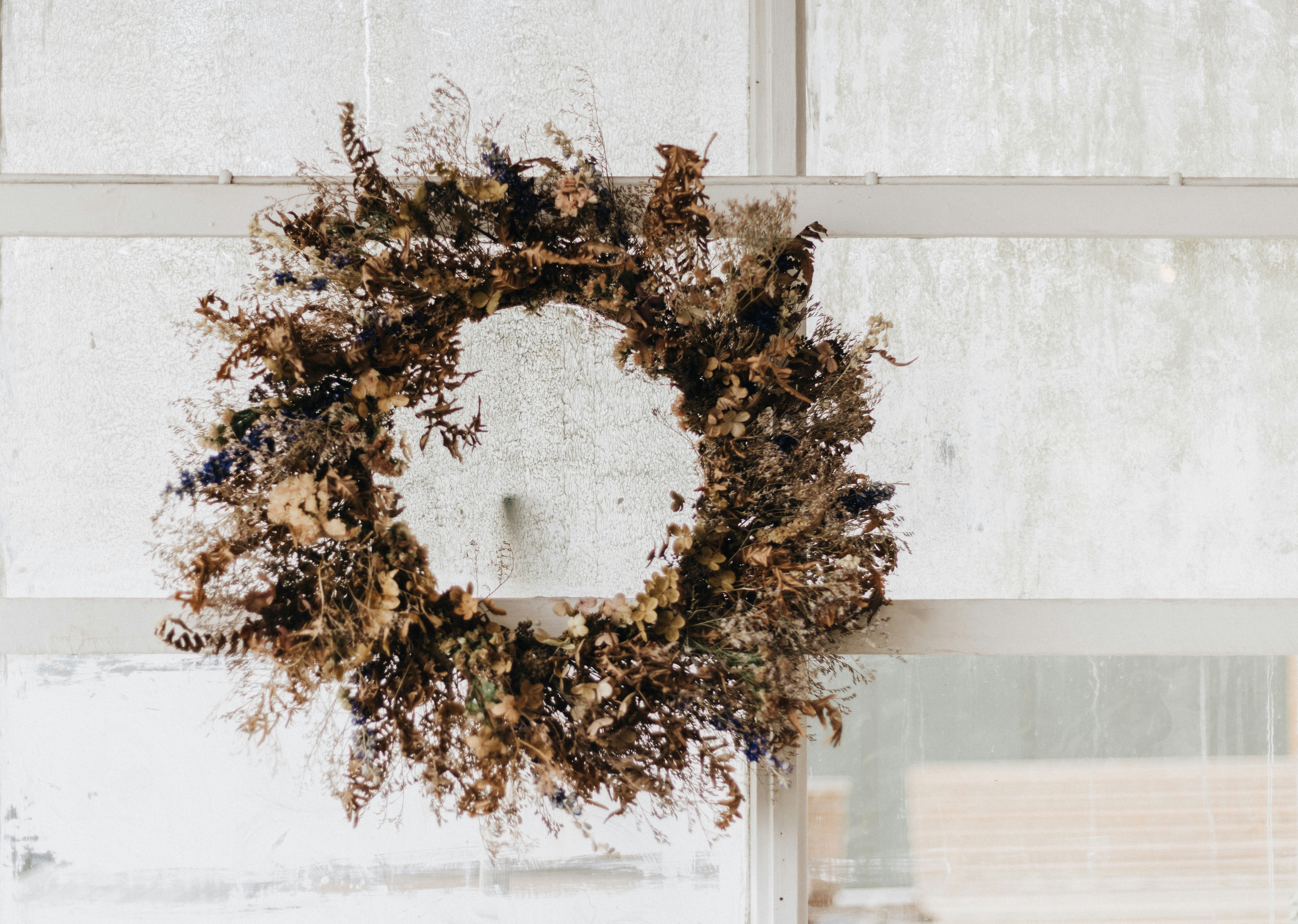 Une couronne séchée accrochée au rebord d’une fenêtre