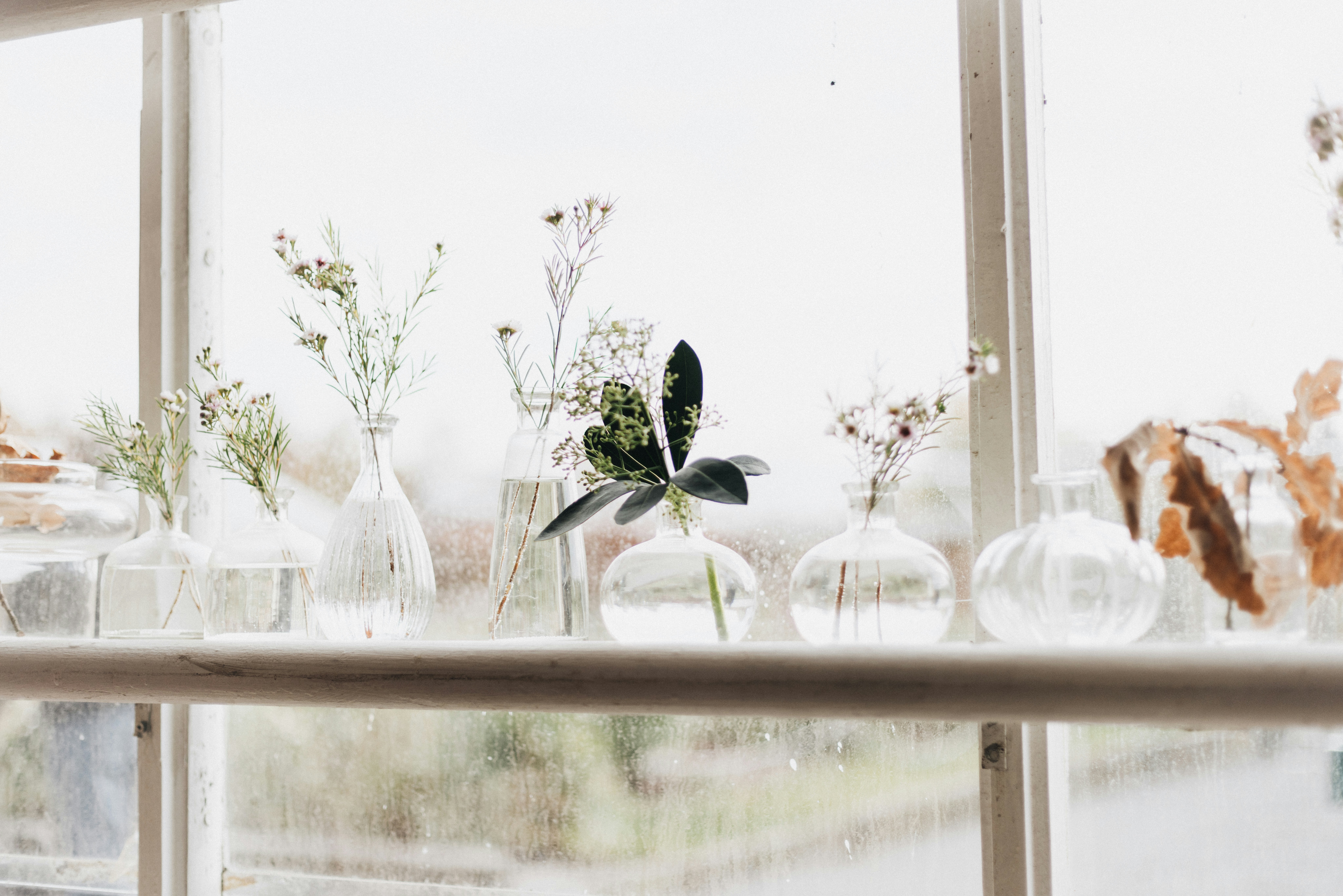 A window sill filled with lots of glass vases
