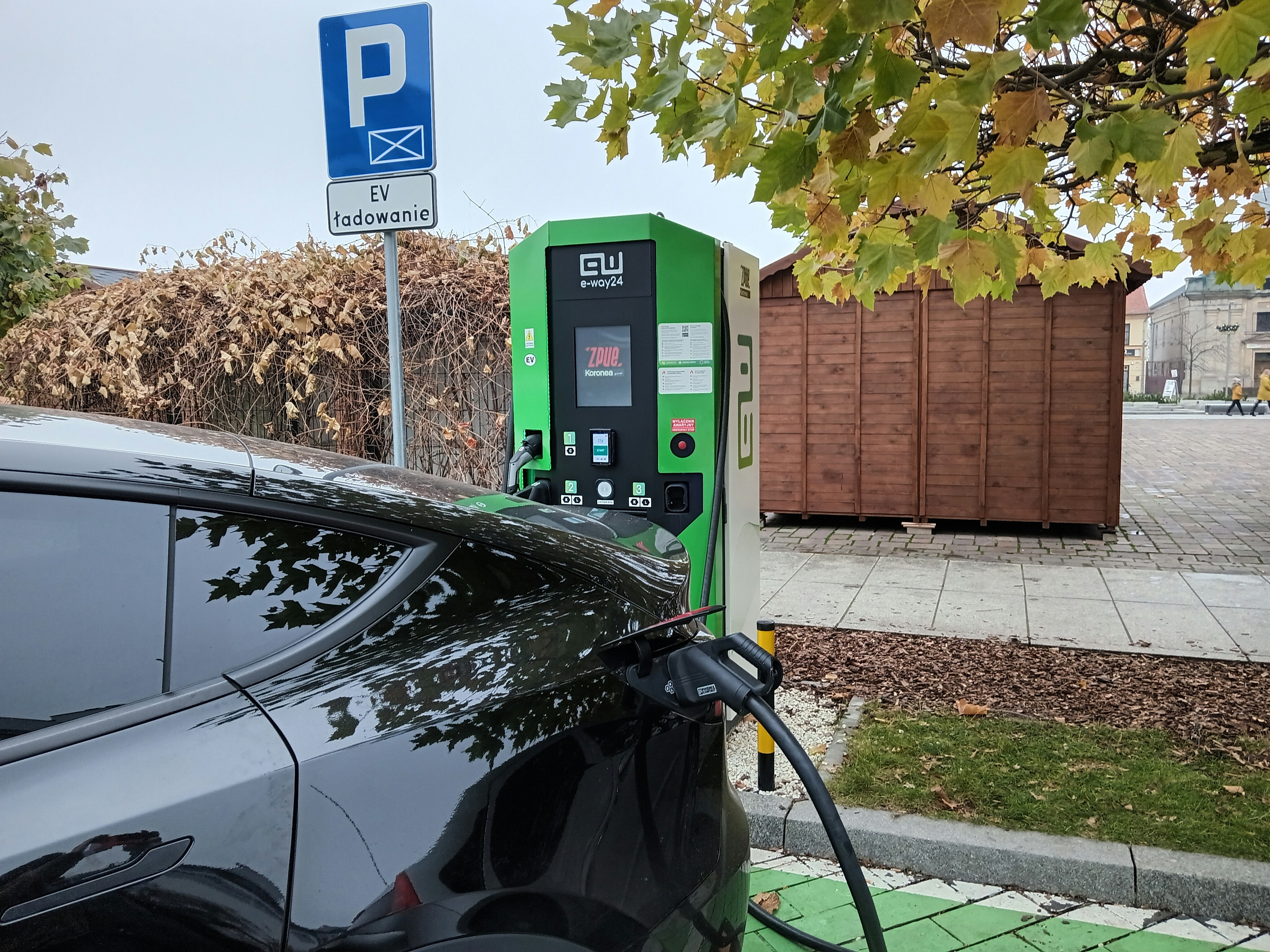 Electric vehicle being charged at a public charging station in an urban setting, showing the growing EV infrastructure