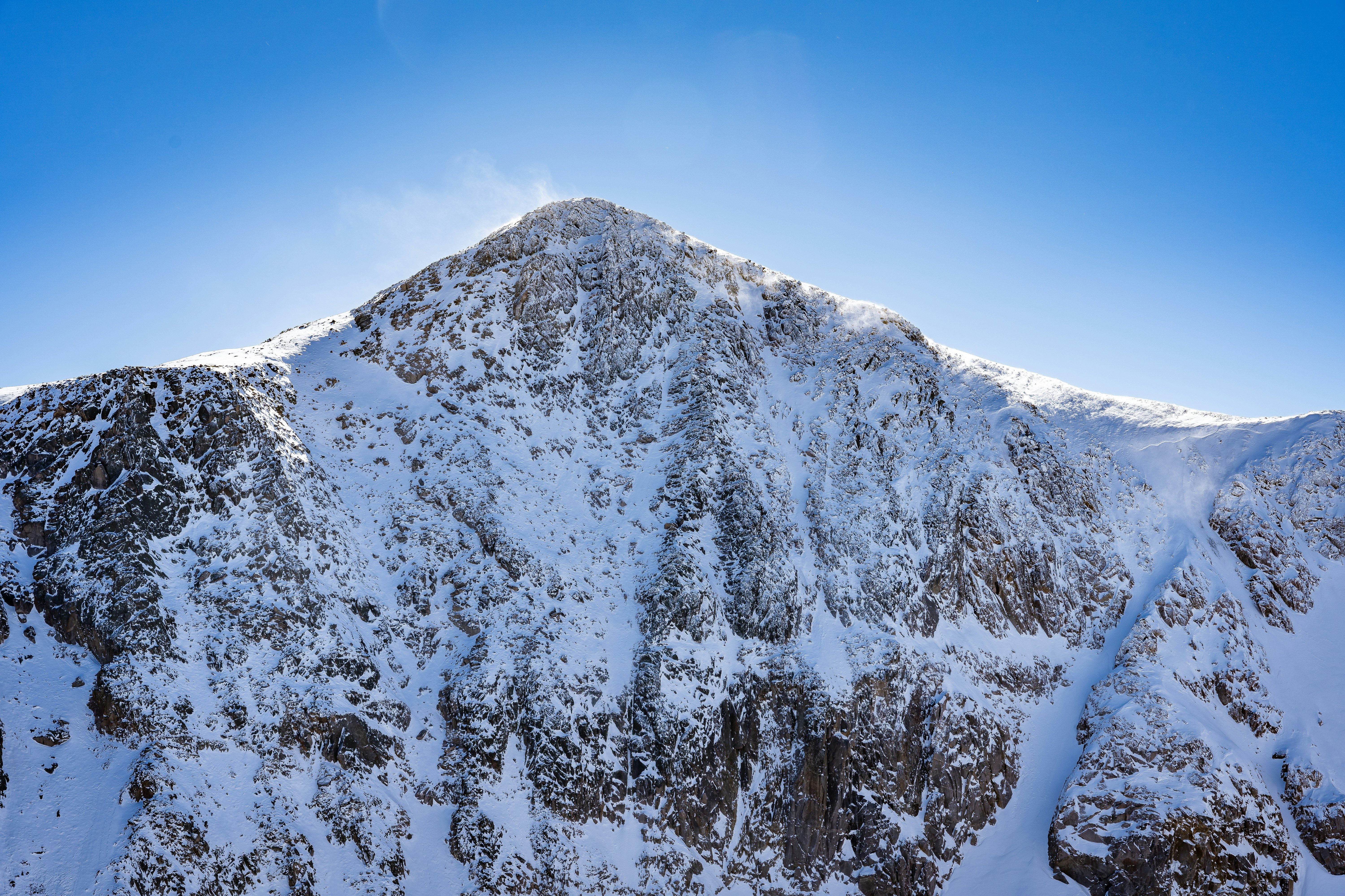 A mountain covered in snow under a blue sky