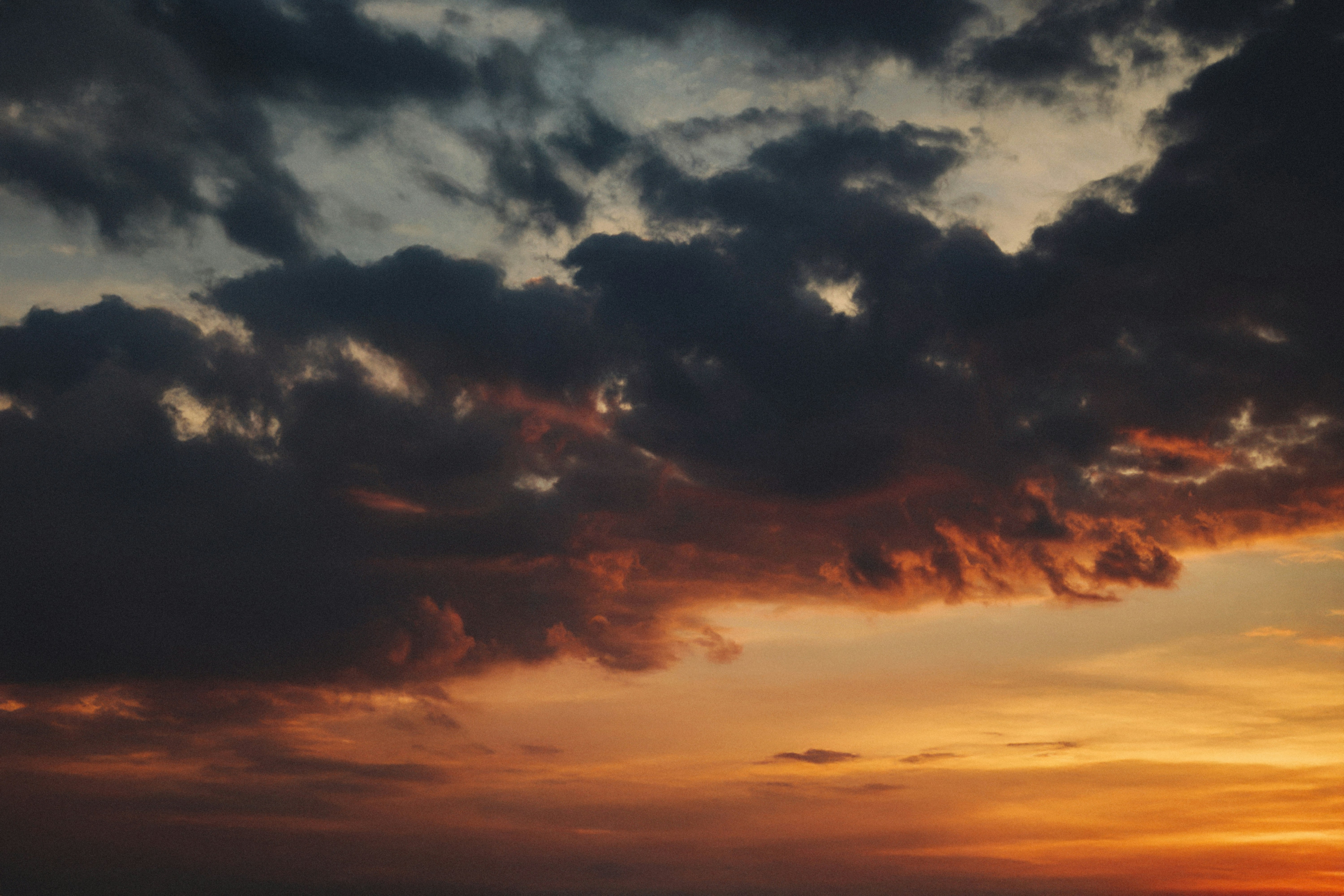 The sun is setting over the ocean with clouds in the sky