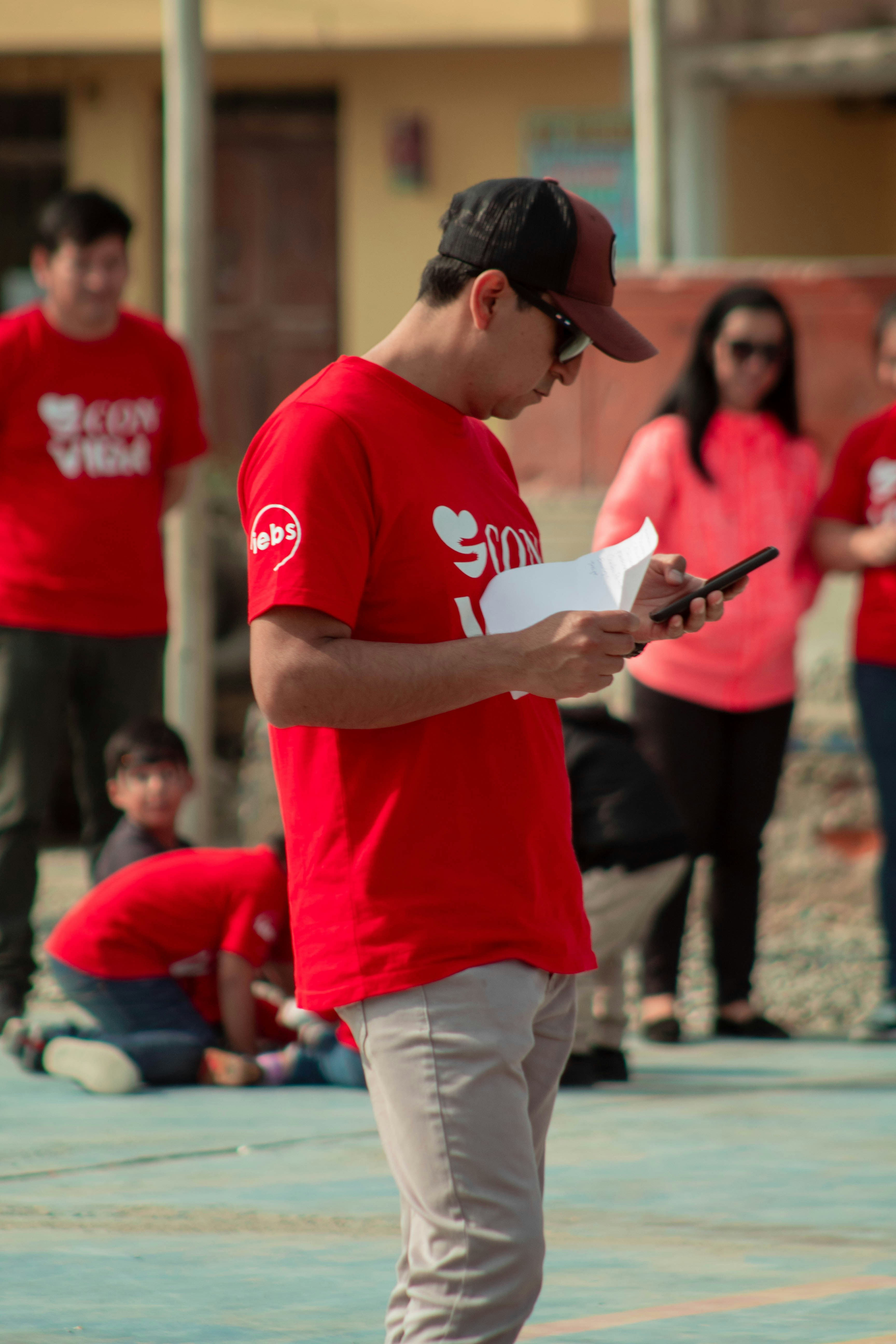 A man in a red shirt is looking at his cell phone