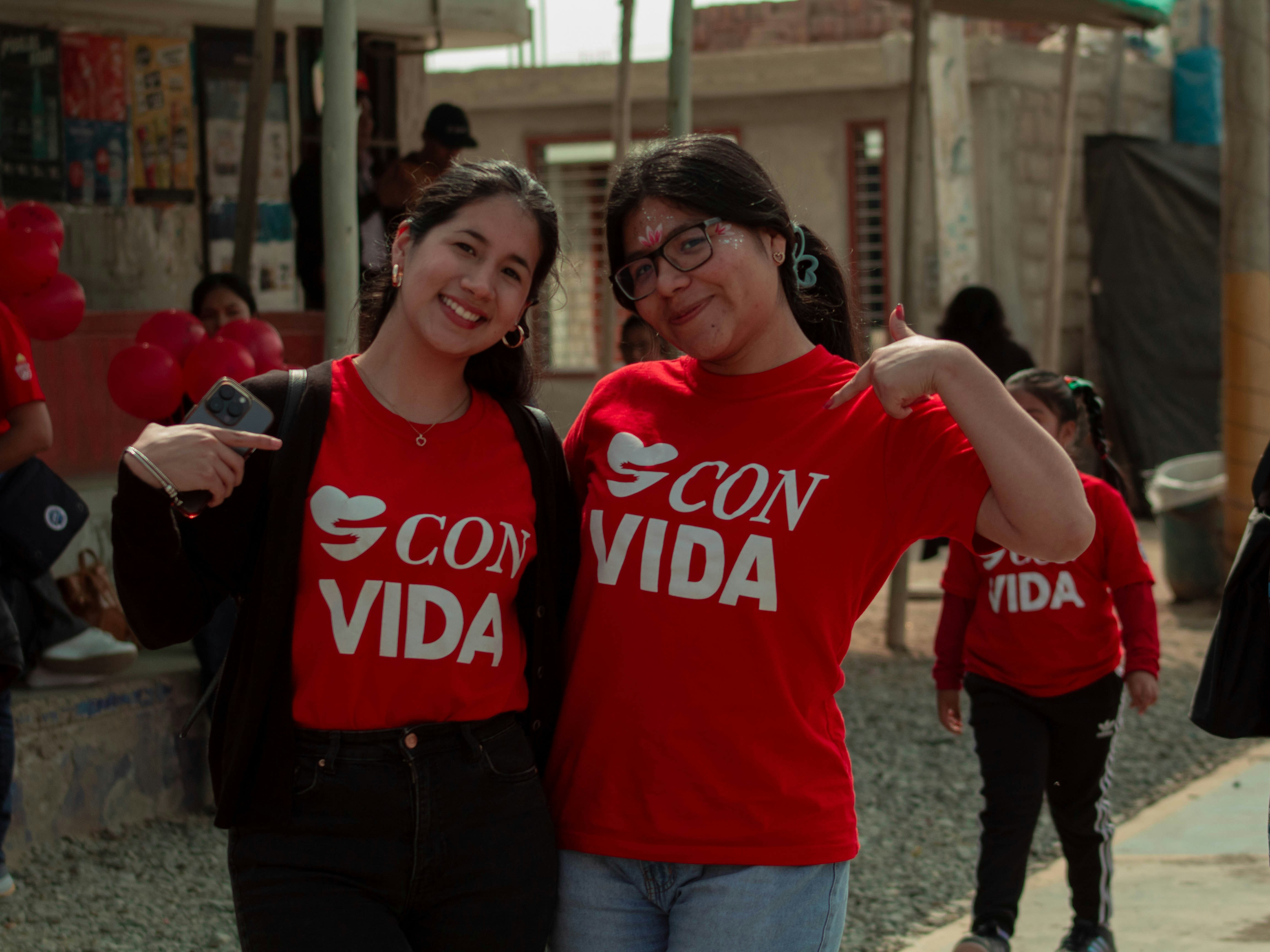 Two women in red shirts standing next to each other