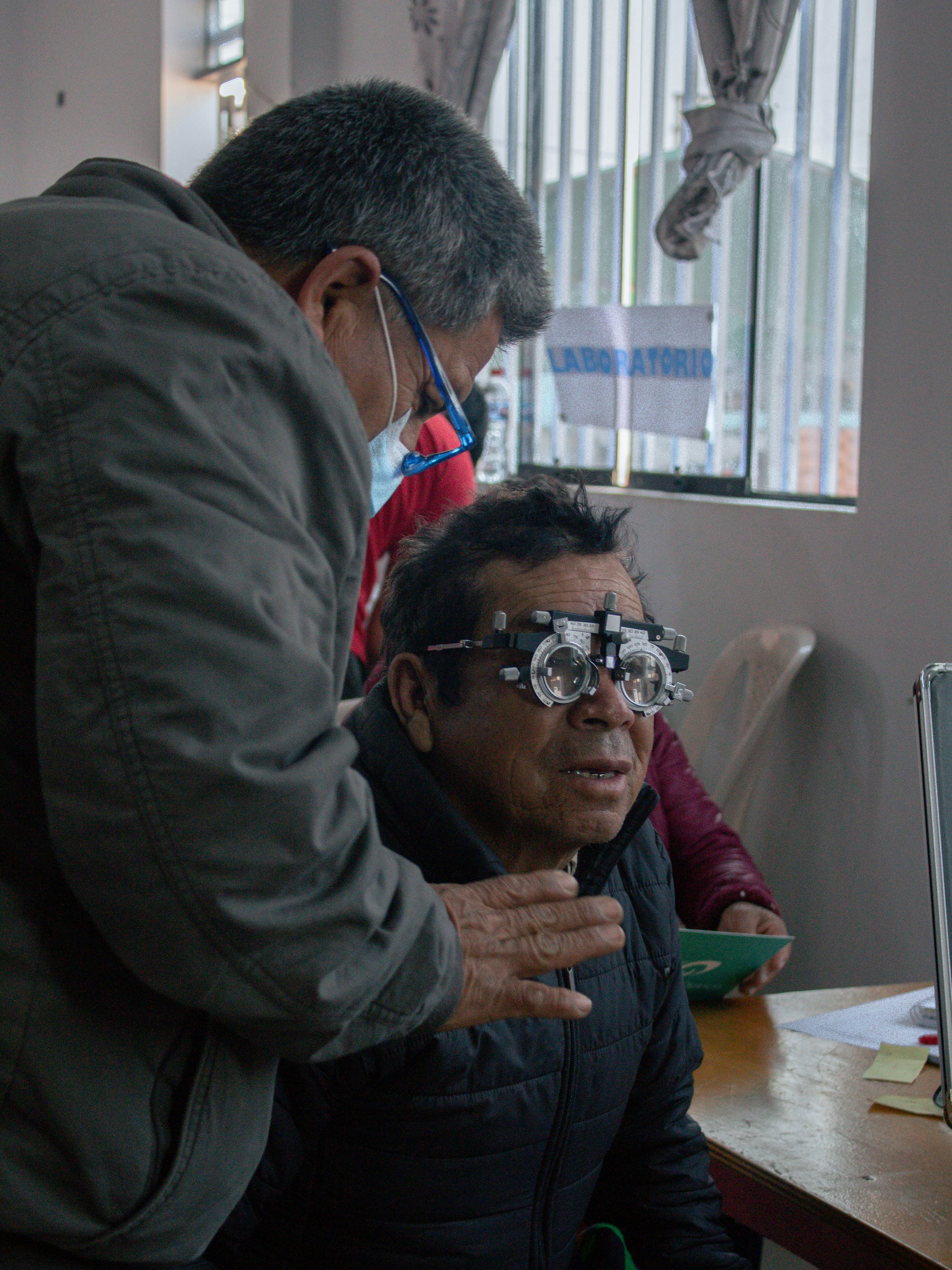 A man looking at a computer screen while another man looks on