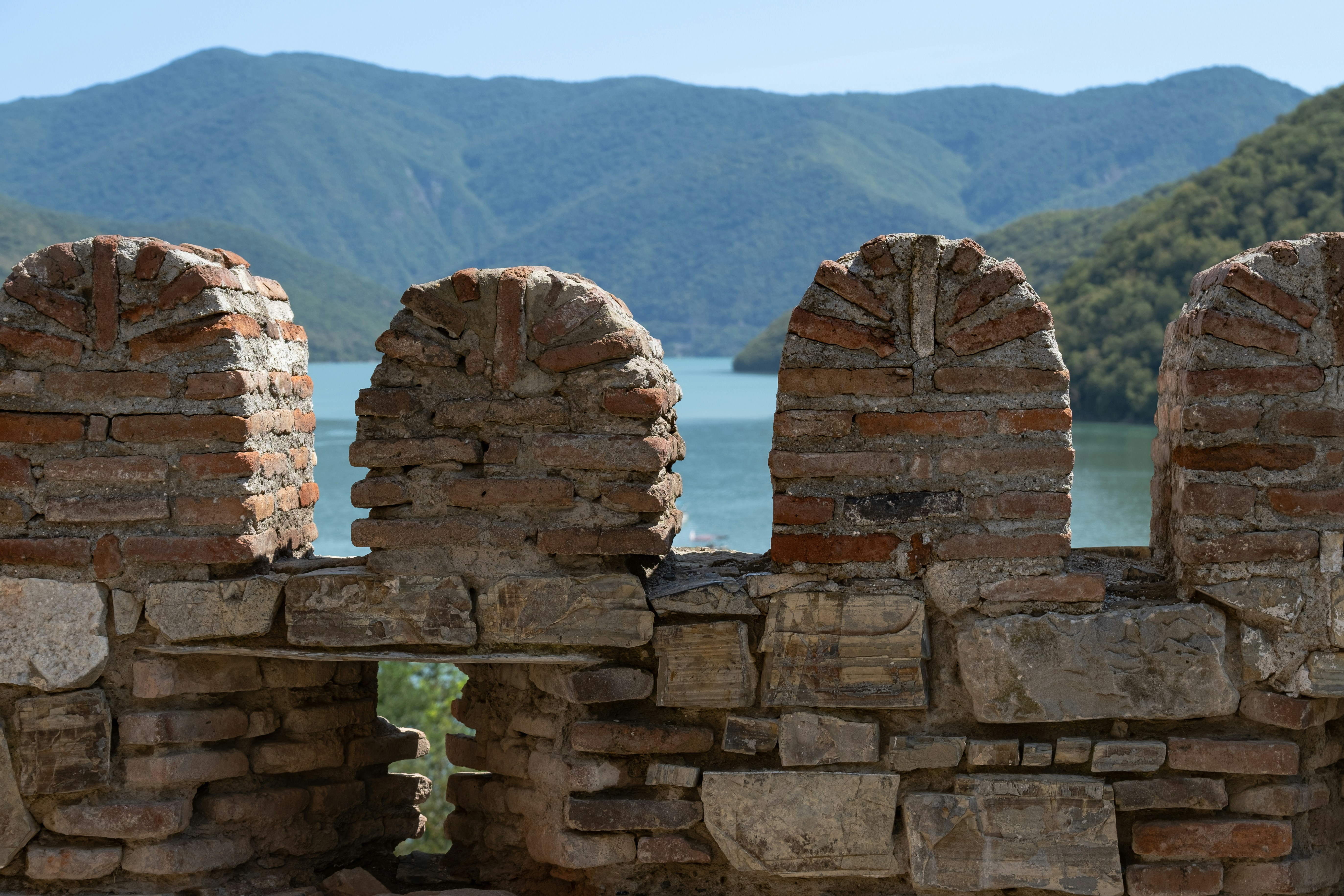 A stone wall with a view of a lake and mountains