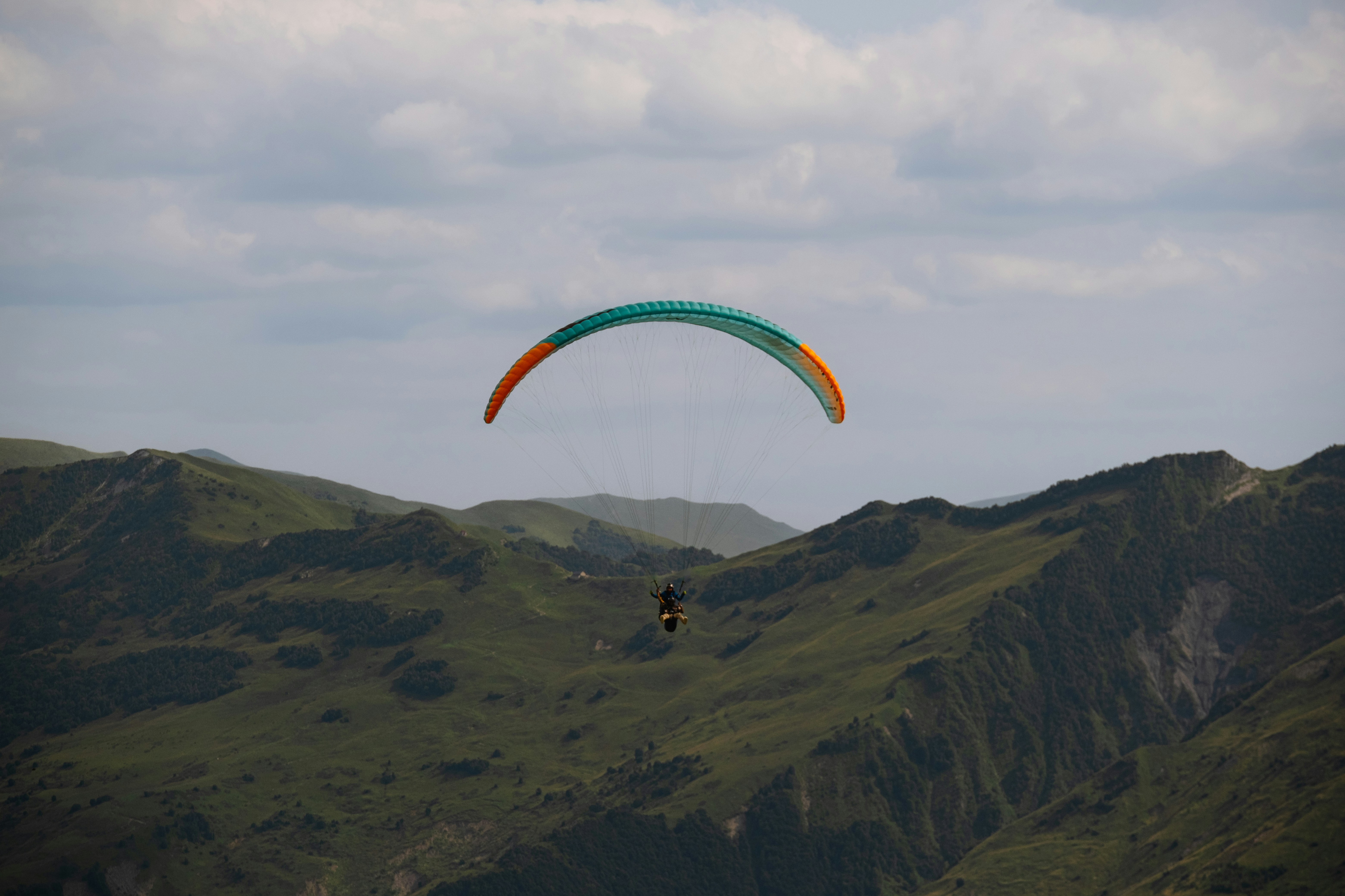 A paraglider is flying over a mountain range