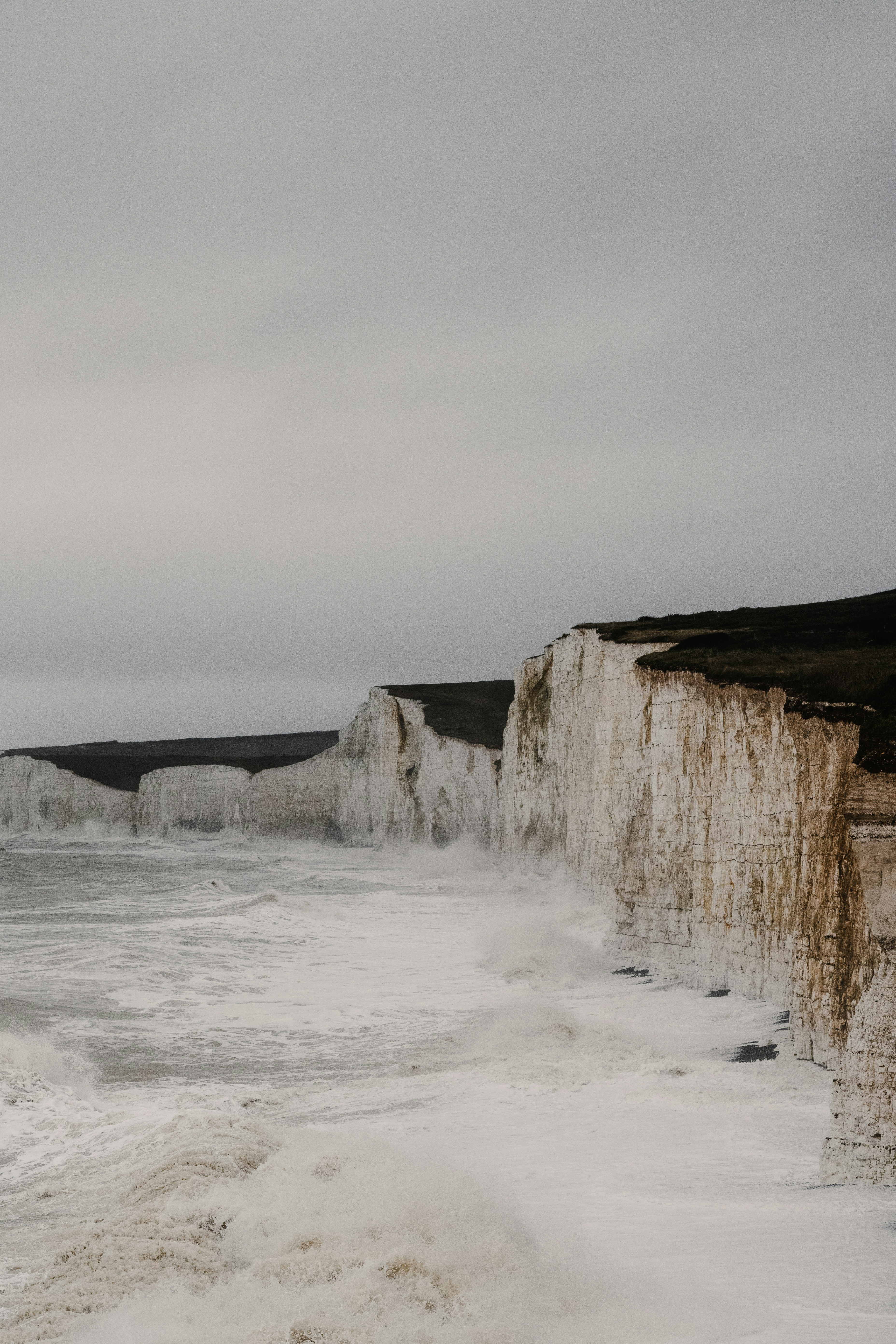 A man standing on the edge of a cliff next to the ocean