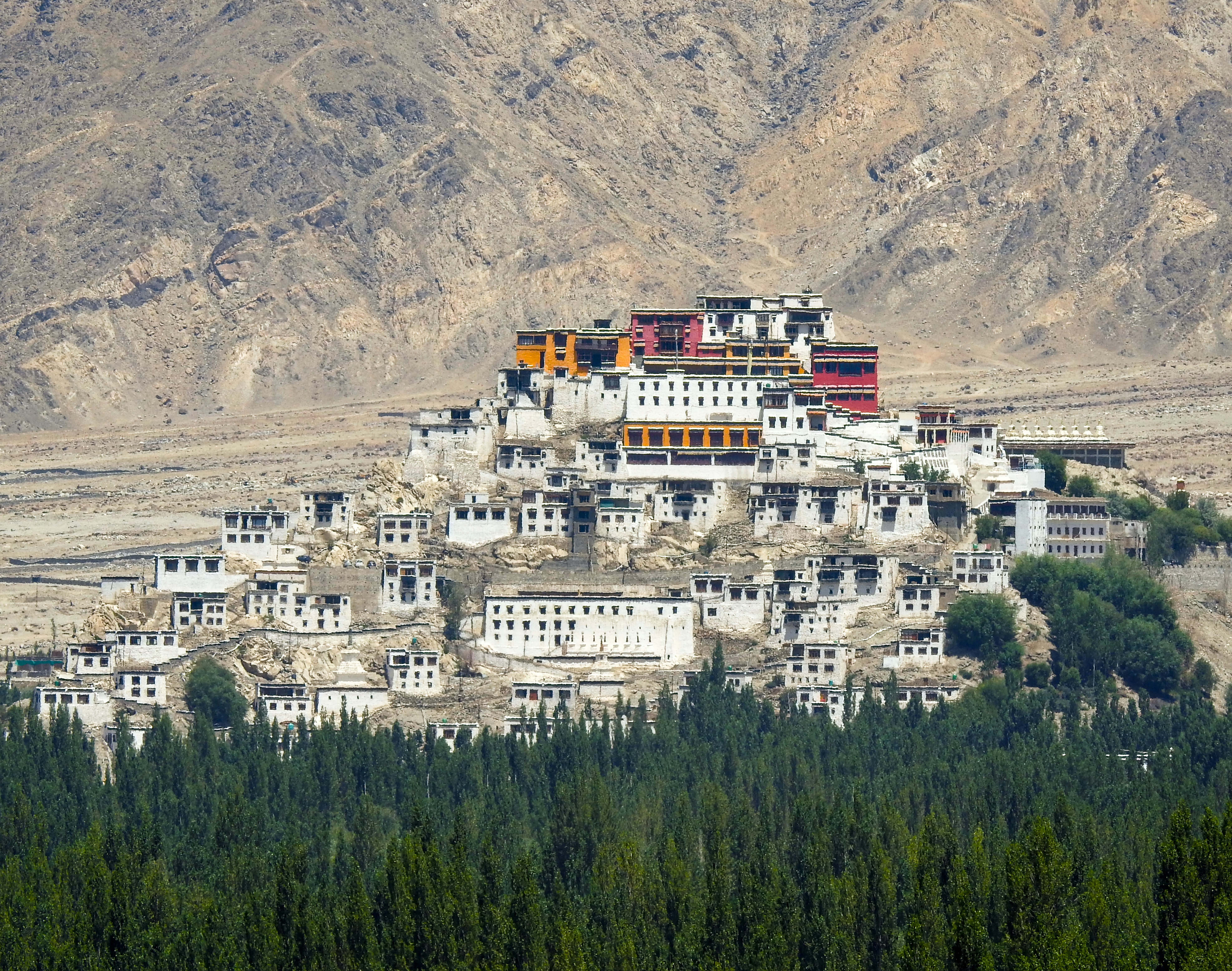 A large white building sitting on top of a lush green hillside