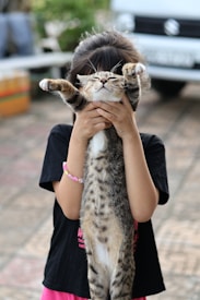 A little girl holding a cat up to her face