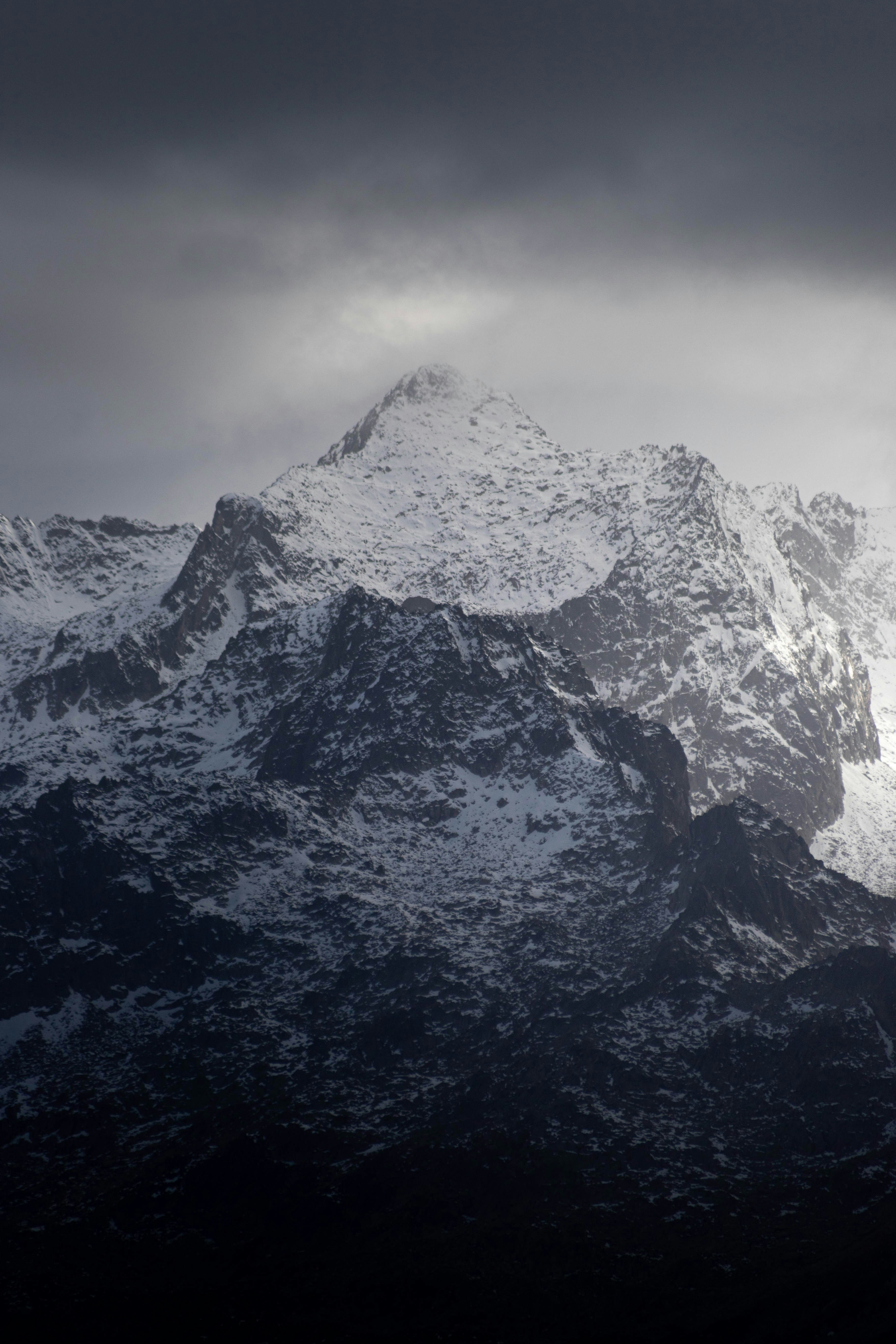 A mountain covered in snow under a cloudy sky