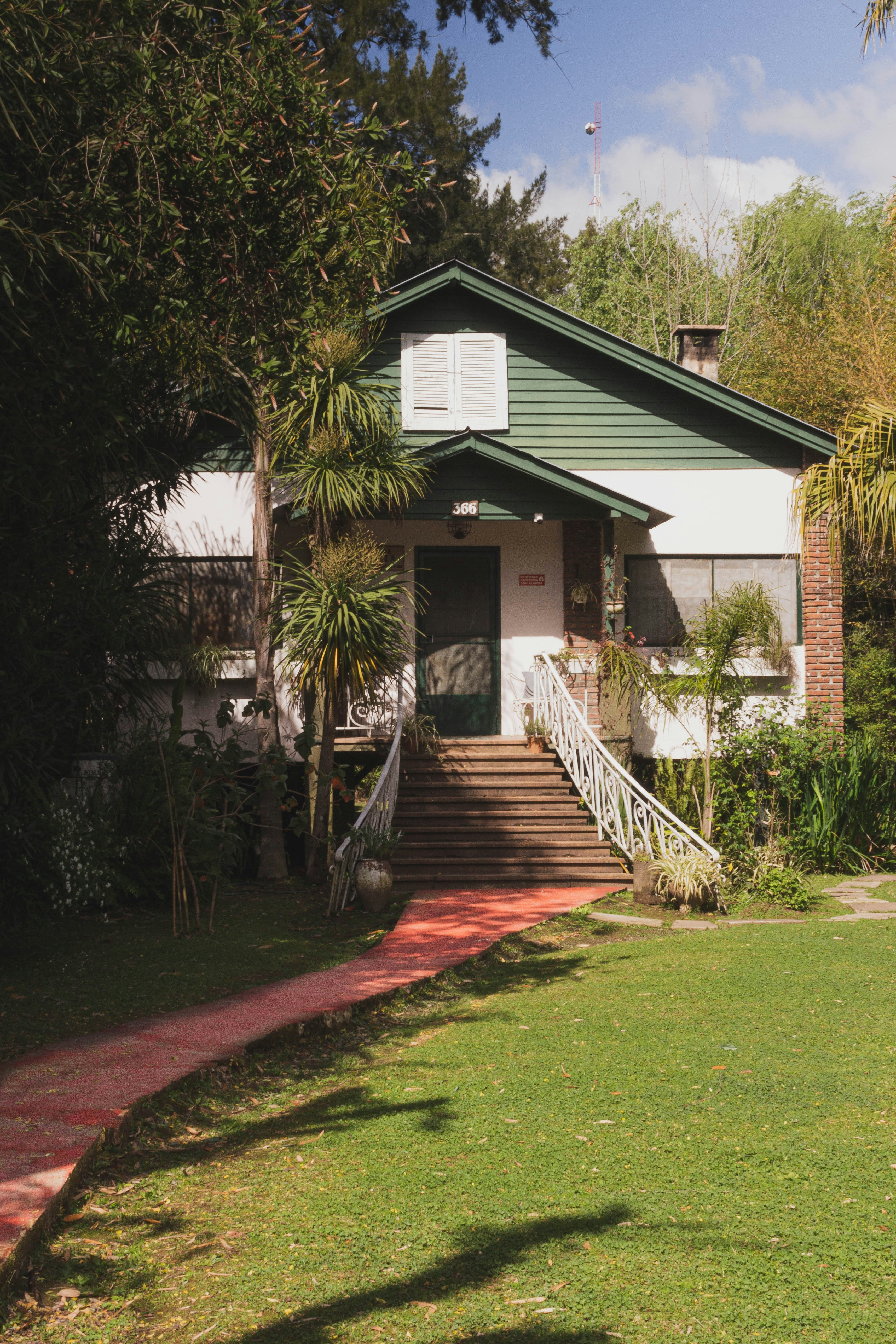A green house with a red brick walkway leading to it