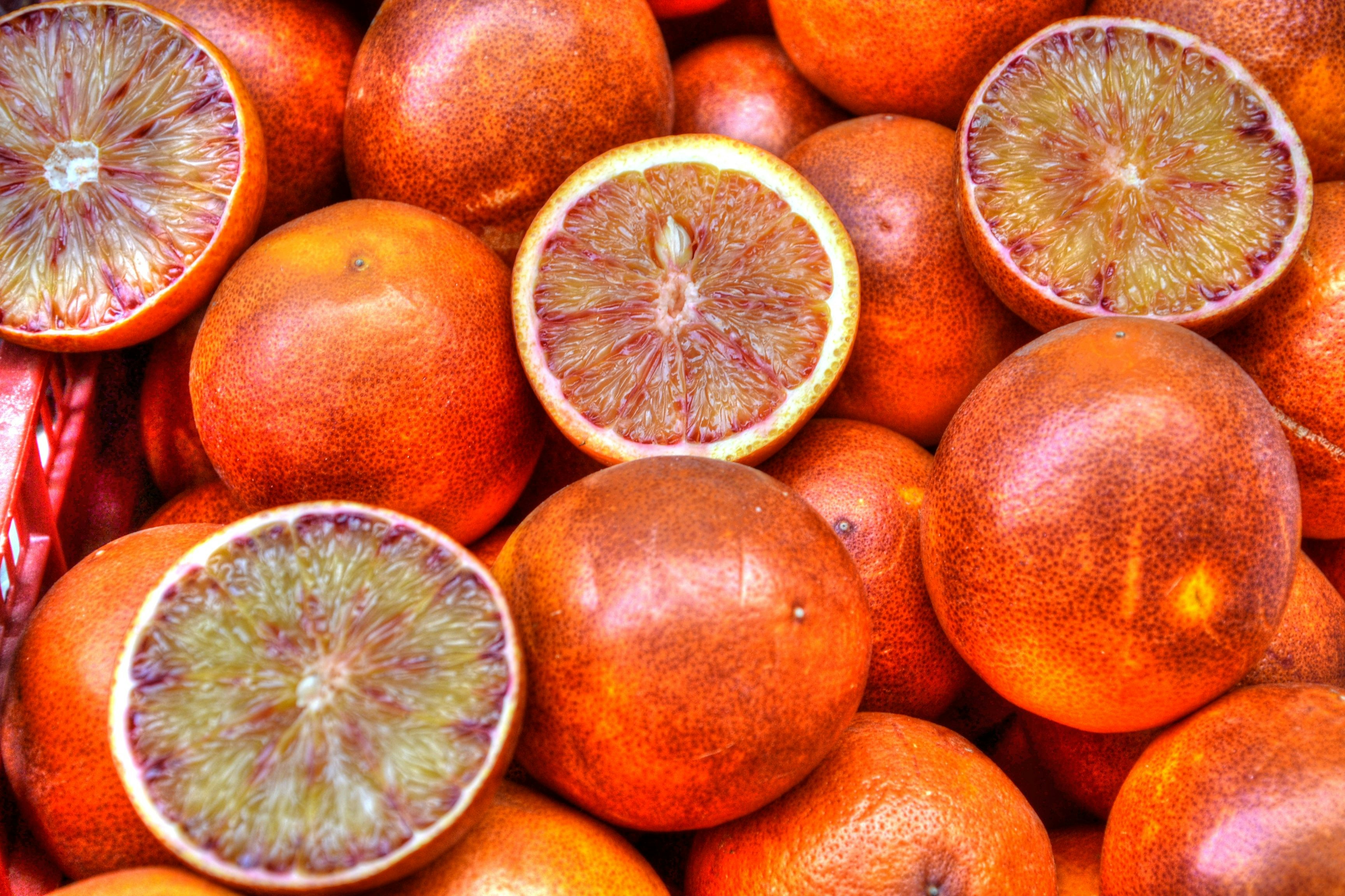 Bright orange Cara Cara navel oranges with one cut open showing pink interior