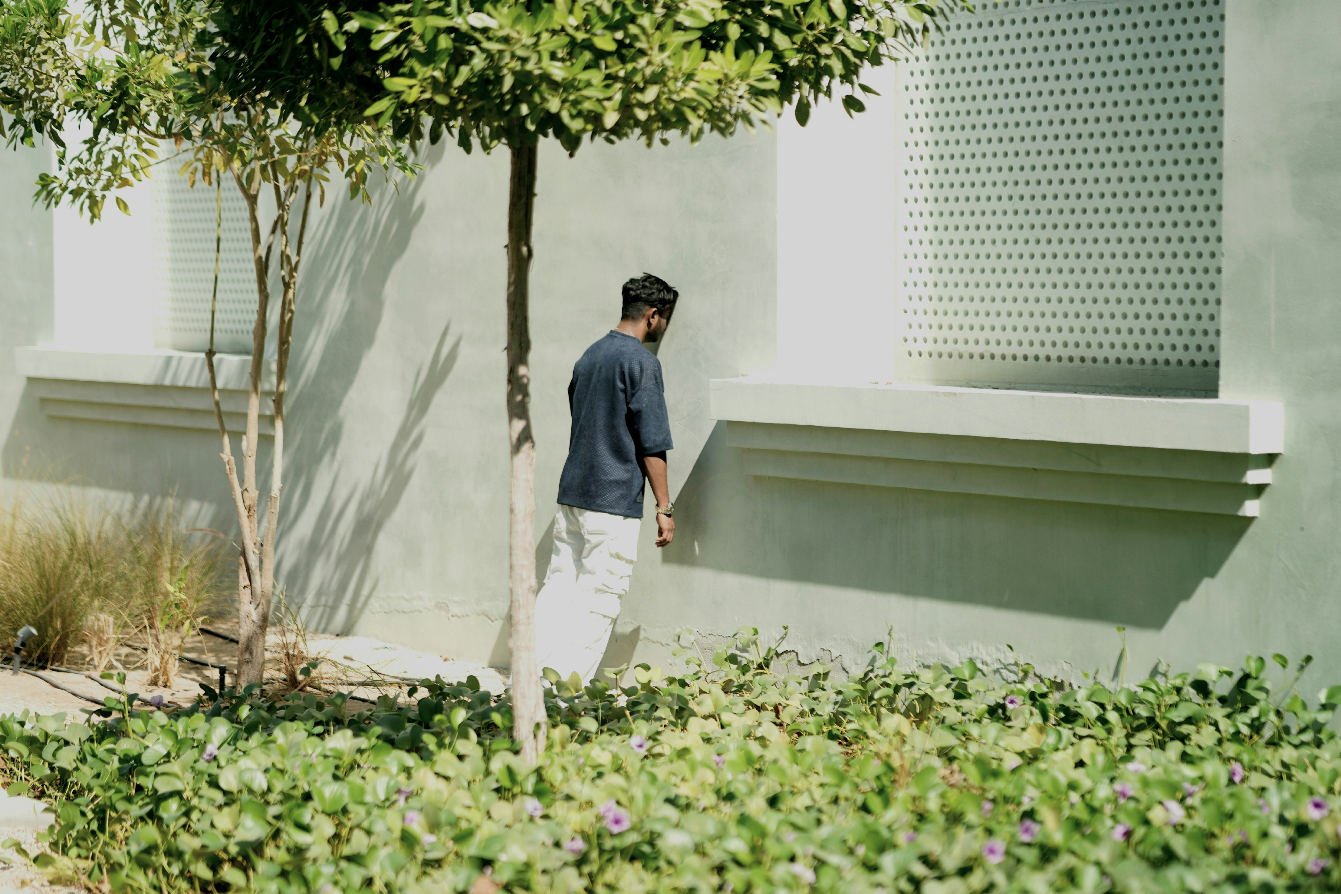 A man standing next to a tree in front of a building