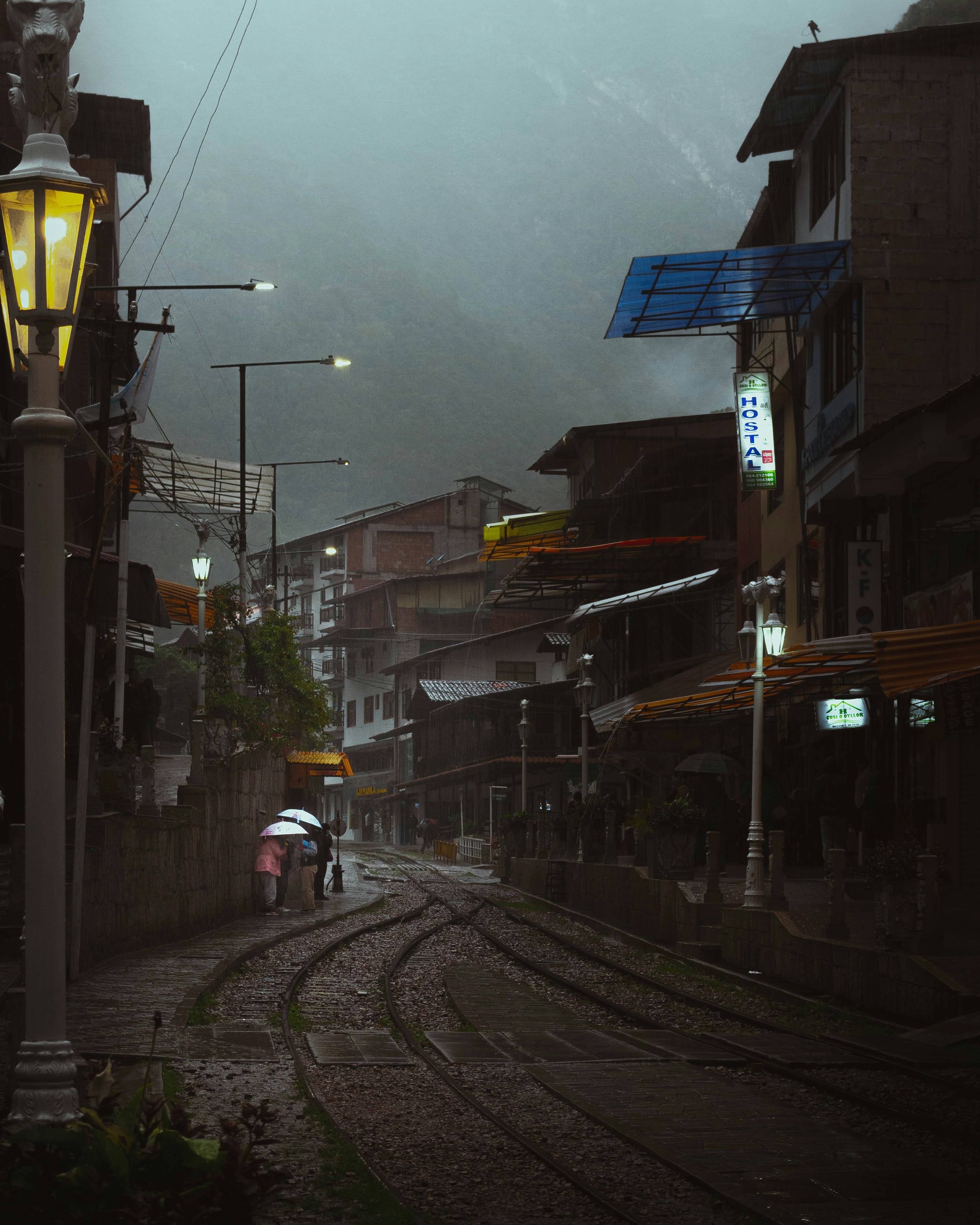 A couple of people walking down a street holding umbrellas